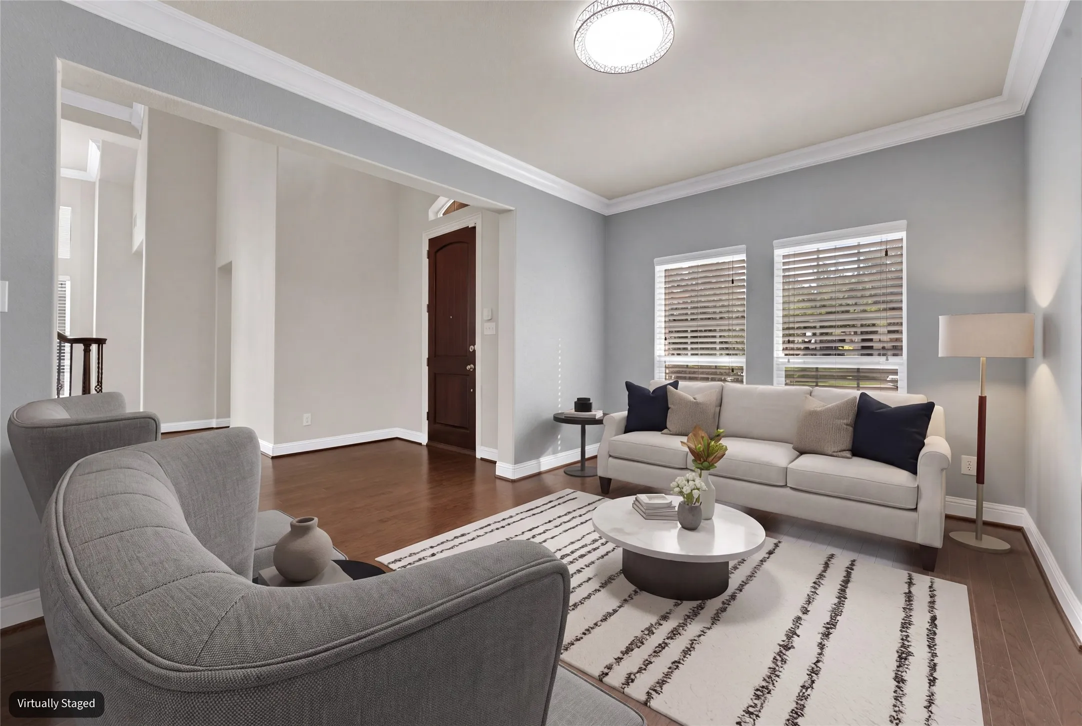 Wood-finish flooring throughout, bright walls, crown molding, and multiple windows with blinds