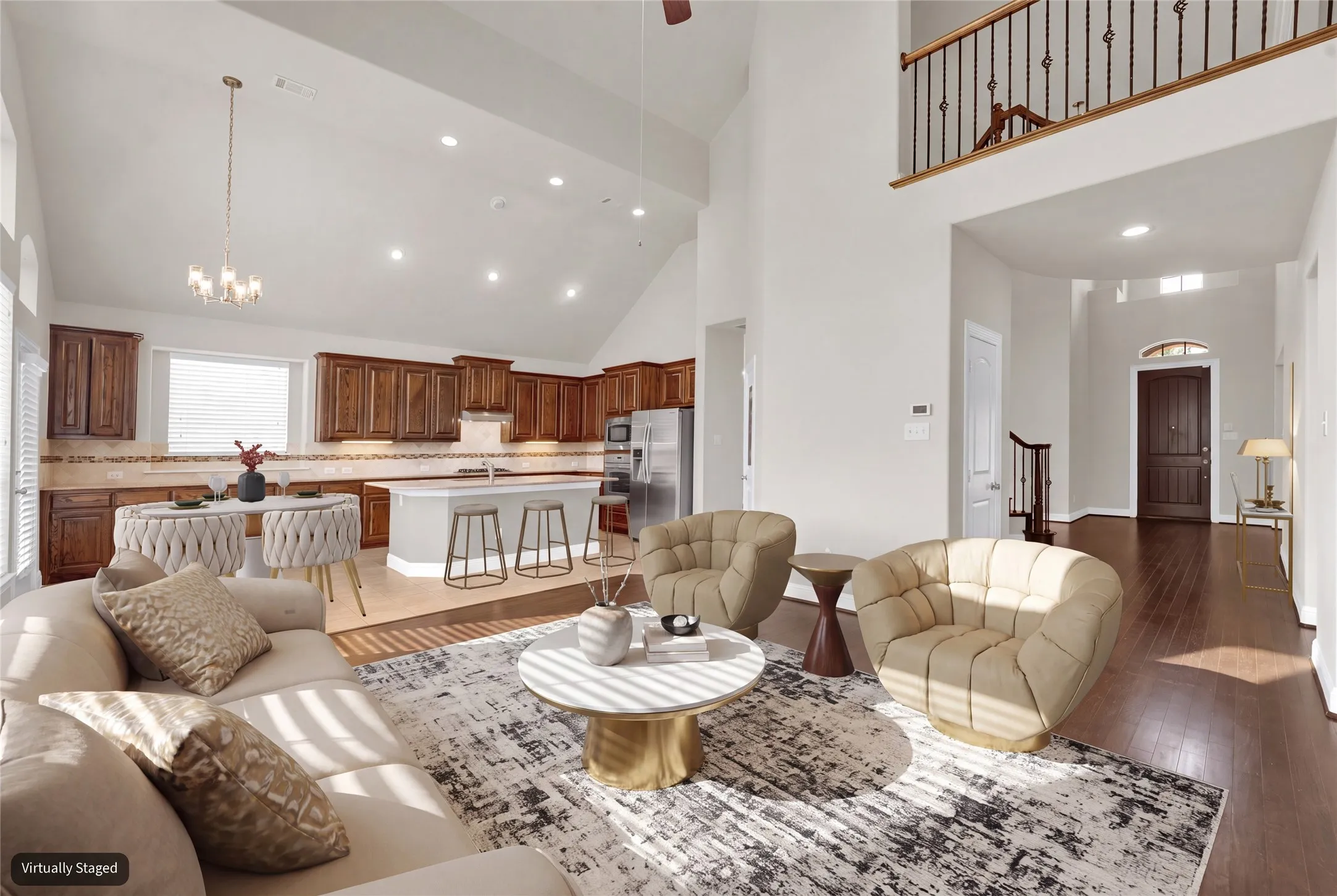 Vaulted ceilings, recessed lighting, wood-finish flooring, island kitchen with integrated appliances, and a second-story interior balcony with wrought iron balusters