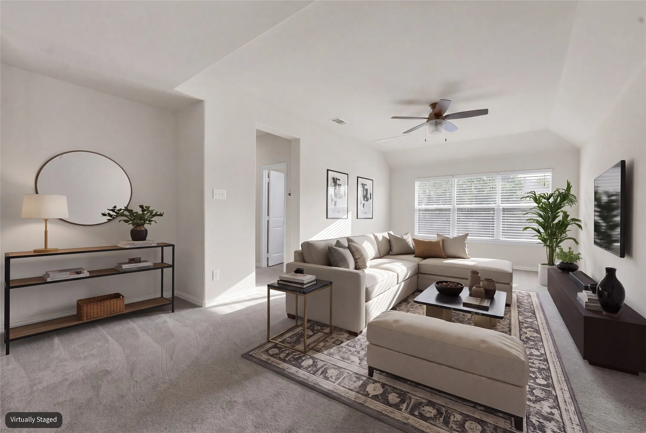 Vaulted ceilings, a multi-pane window, and a ceiling fan are featured in this carpeted living area