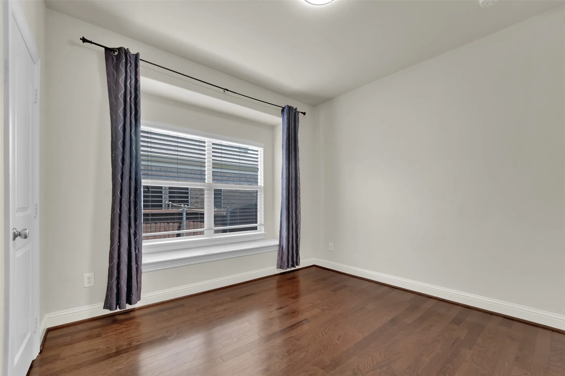 Wood-finish flooring, white walls, white trim, and a window with blinds