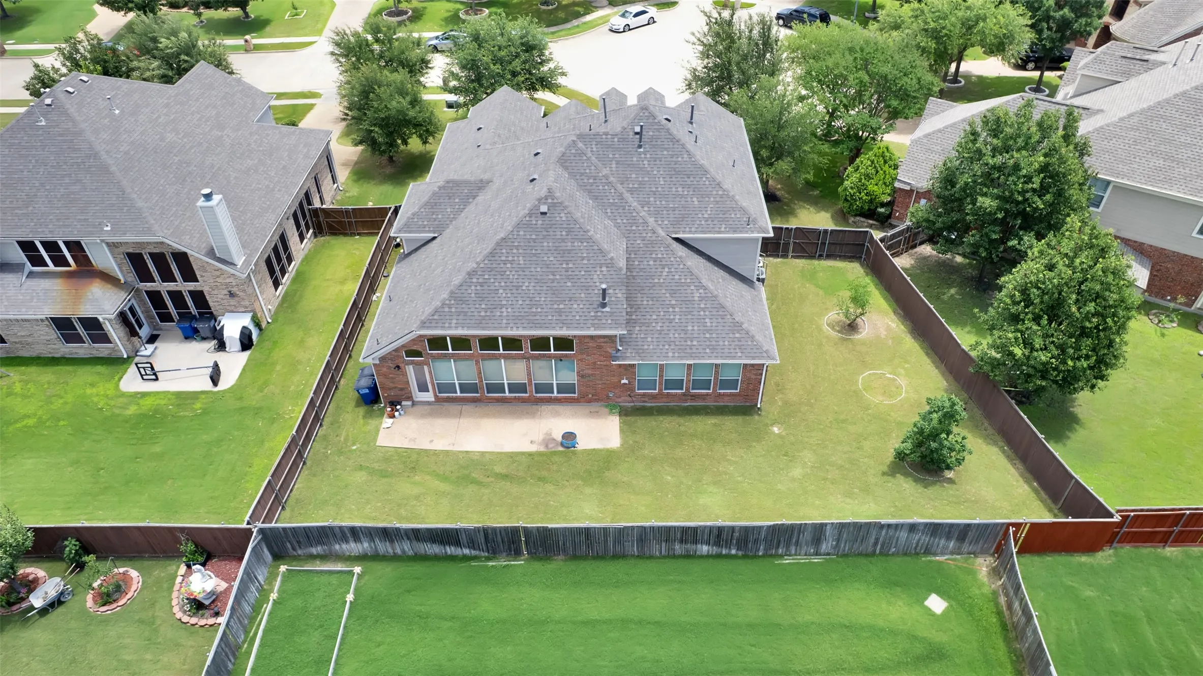 Expansive rear yard with a paved patio, mature trees, and privacy fencing