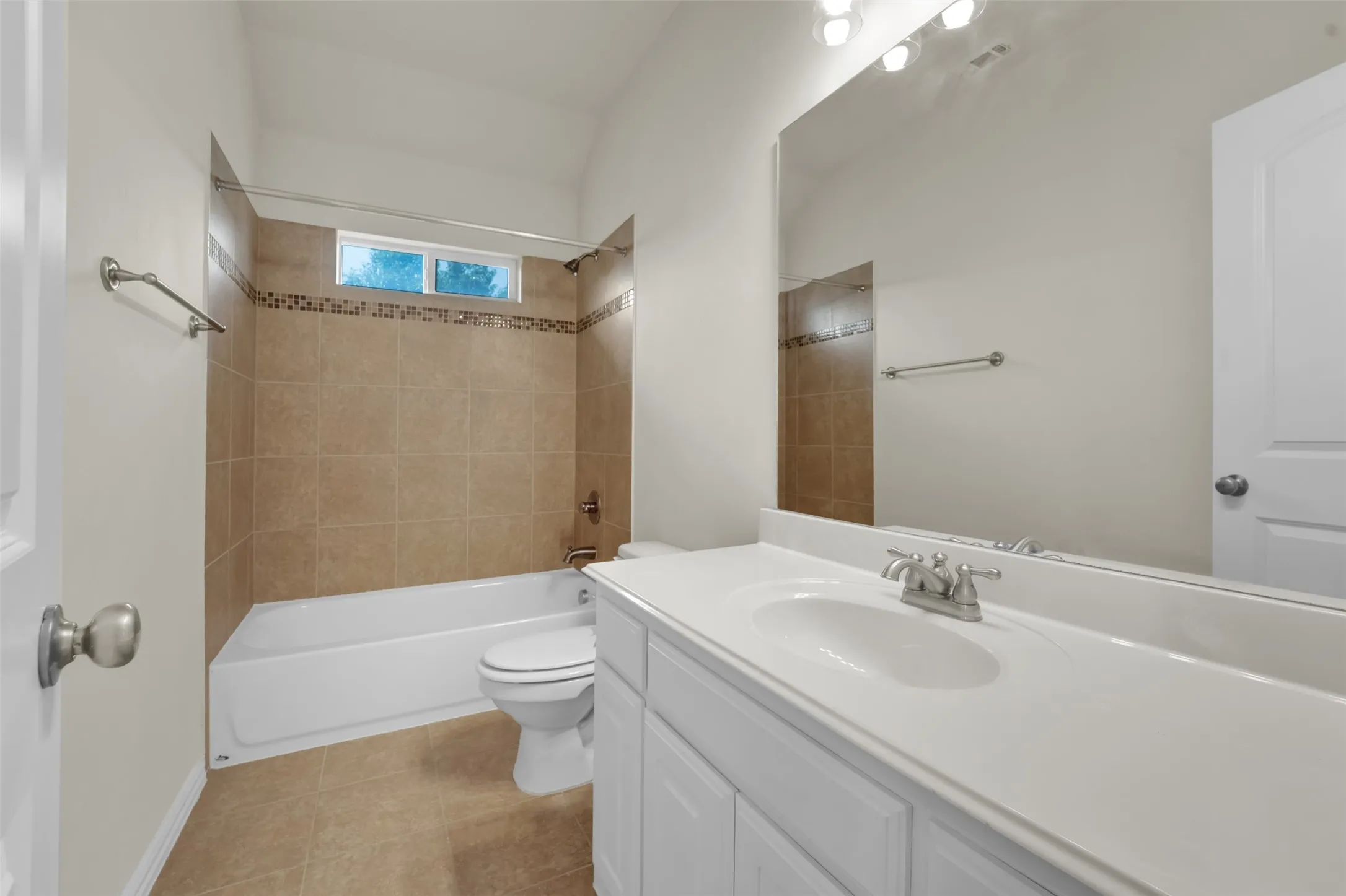 Bathroom featuring a vanity with an integrated sink, a large wall-mounted mirror, and a tub with tiled surround