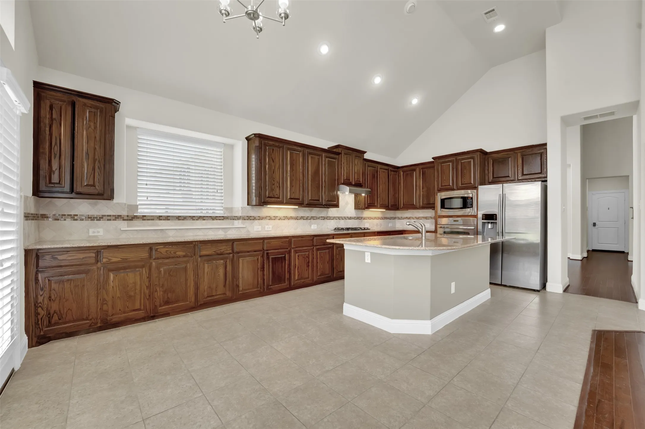 Vaulted ceilings, recessed lighting, wood-finish cabinetry, stainless steel appliances, and a central island with sink