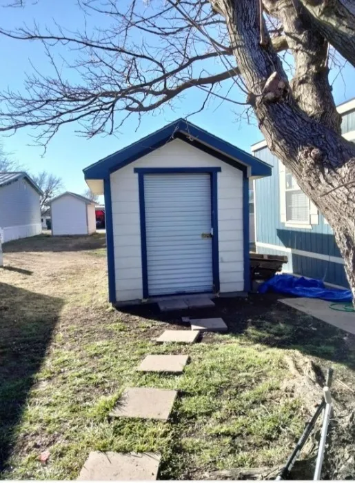 Gable-roof storage shed with a roll-up door and concrete paver pathway
