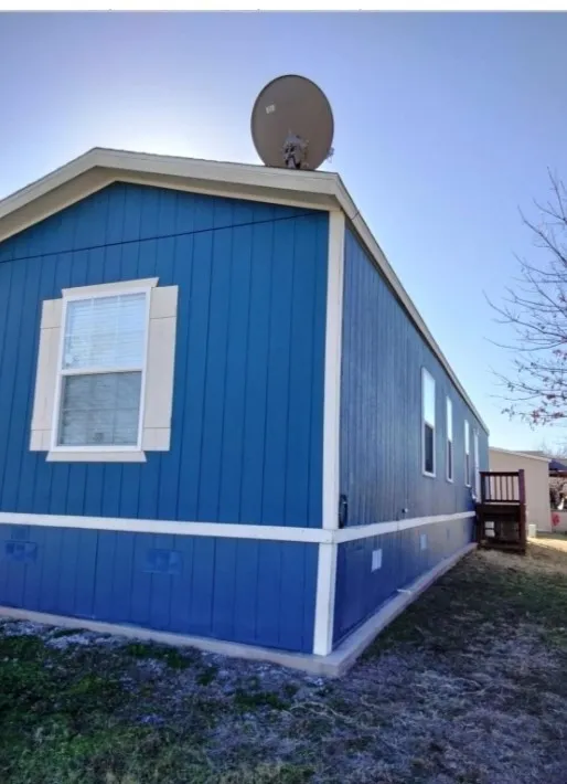 Blue vertical siding exterior with white trim, multiple windows, and a wood-toned deck