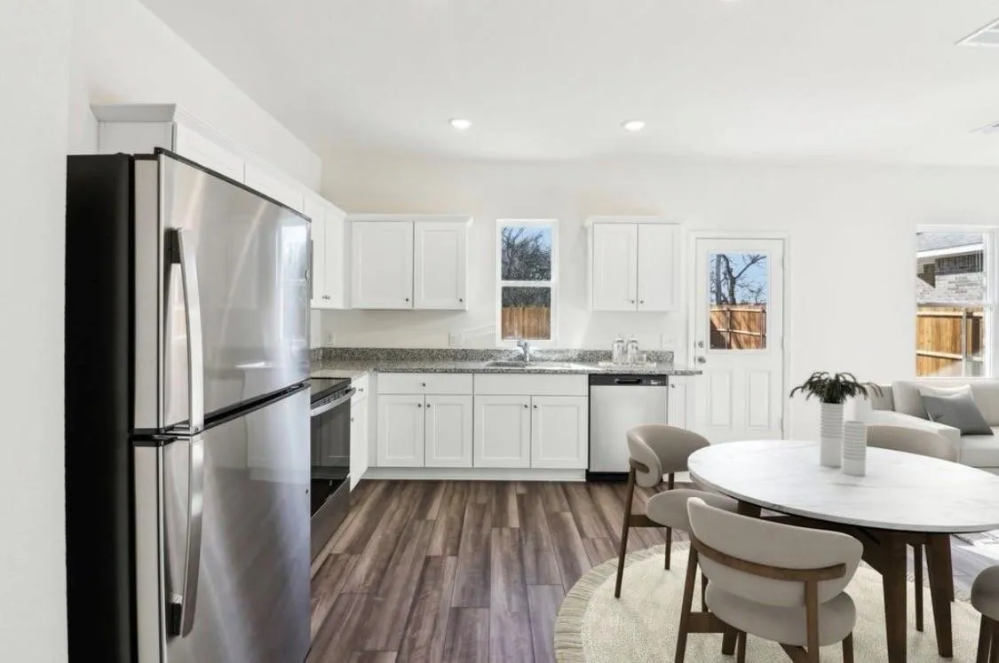 Kitchen featuring stainless steel appliances, white cabinetry, granite-style countertops, wood-finish flooring, and recessed lighting