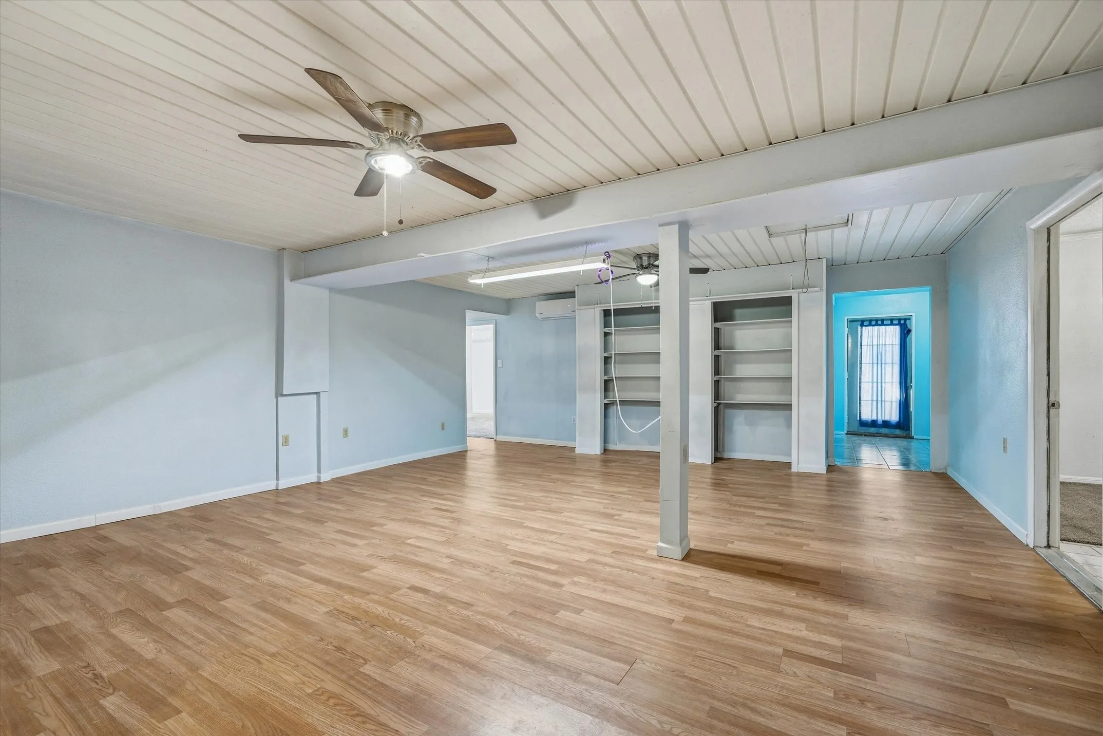 Wood-finish flooring, light blue walls, and a white planked ceiling