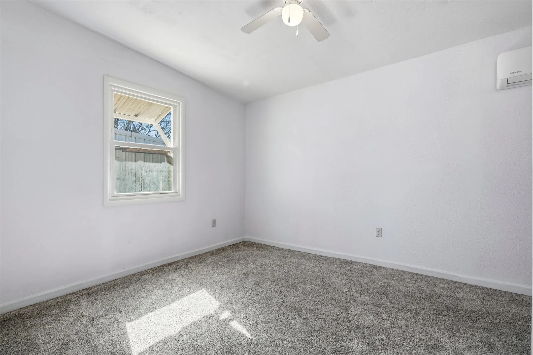 Bright secondary bedroom featuring neutral wall finishes, carpet flooring, a ceiling fan with integrated lighting, and abundant natural light from a large double-hung window