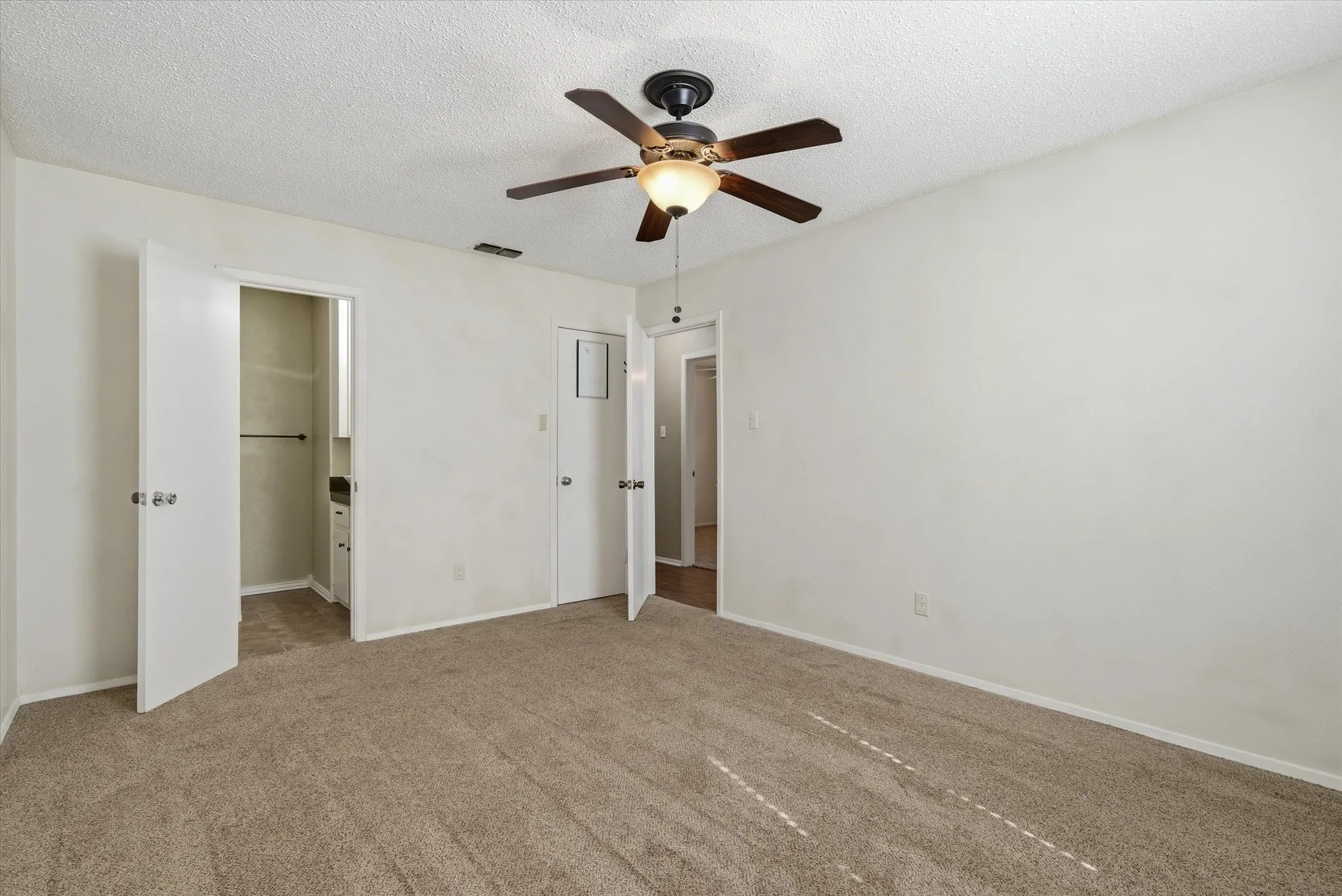 Carpeted flooring throughout, ceiling fan with integrated lighting, and white panel doors