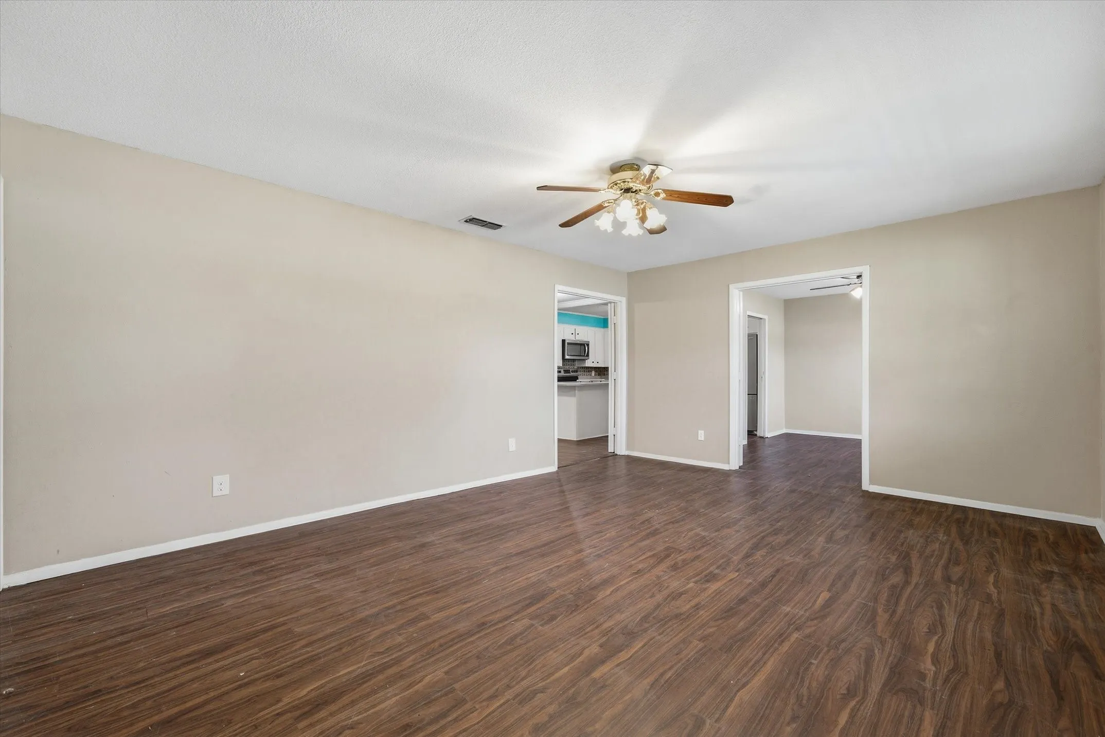 Wood-finish flooring throughout, neutral paint palette, and a ceiling fan with integrated lighting