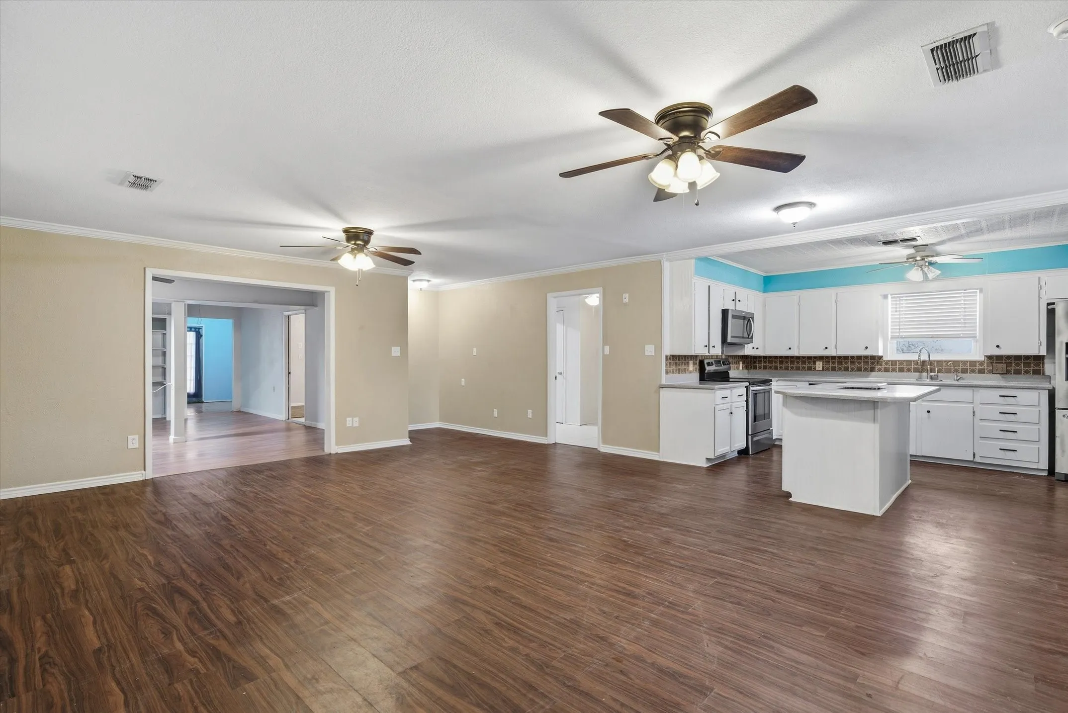 Expansive main living area featuring wood-finish flooring, ceiling fans, and an open concept kitchen