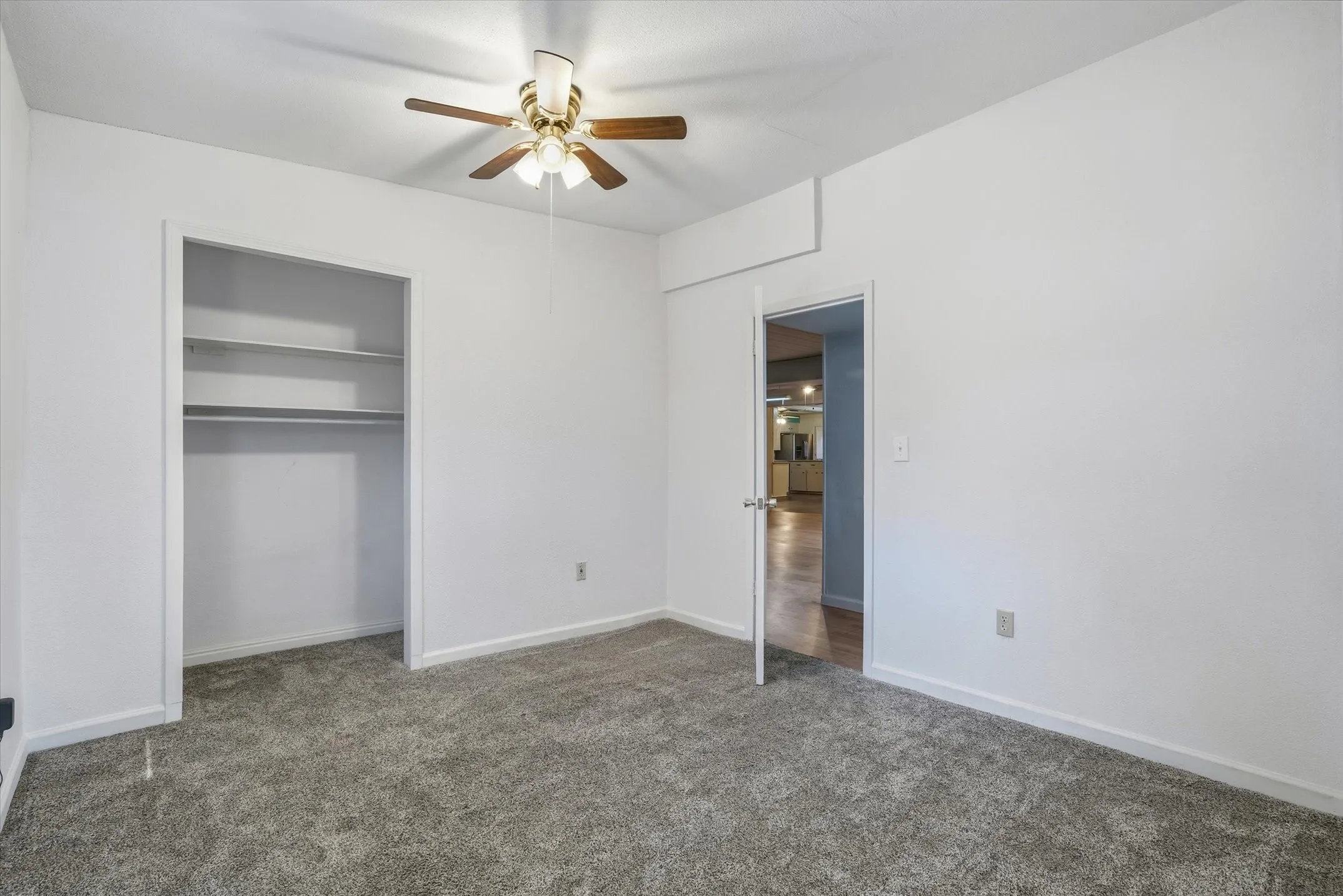 Wall-to-wall carpeting, overhead ceiling fan with light fixture, and closet with built-in shelving and hanging rod