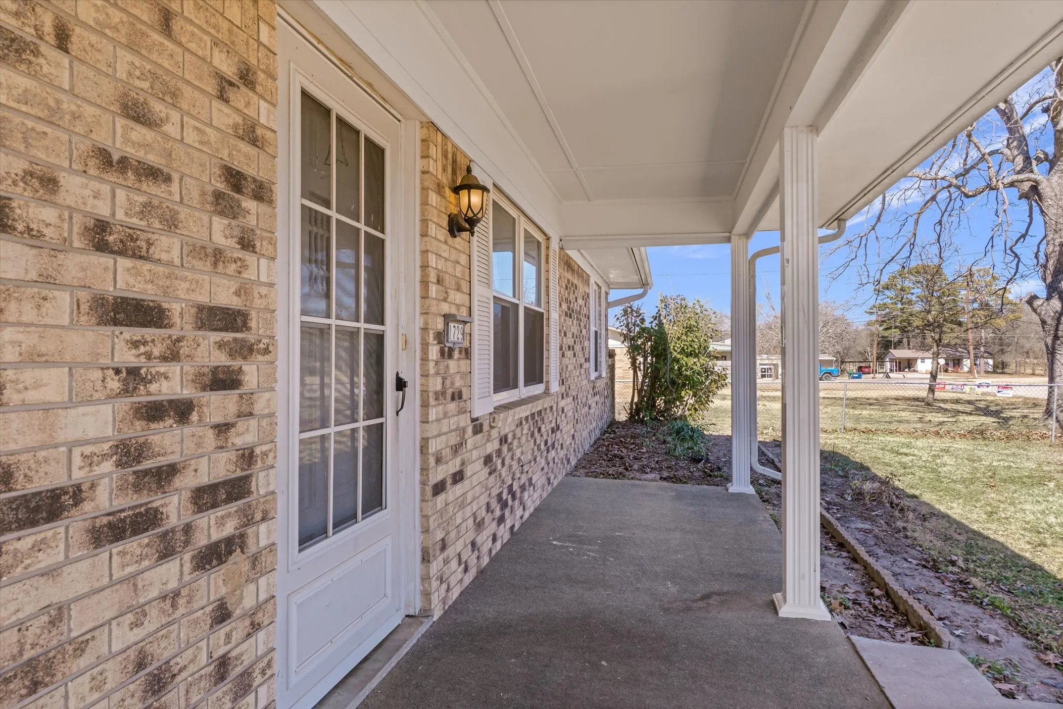 Brick exterior with a covered porch, white columns, and a storm door
