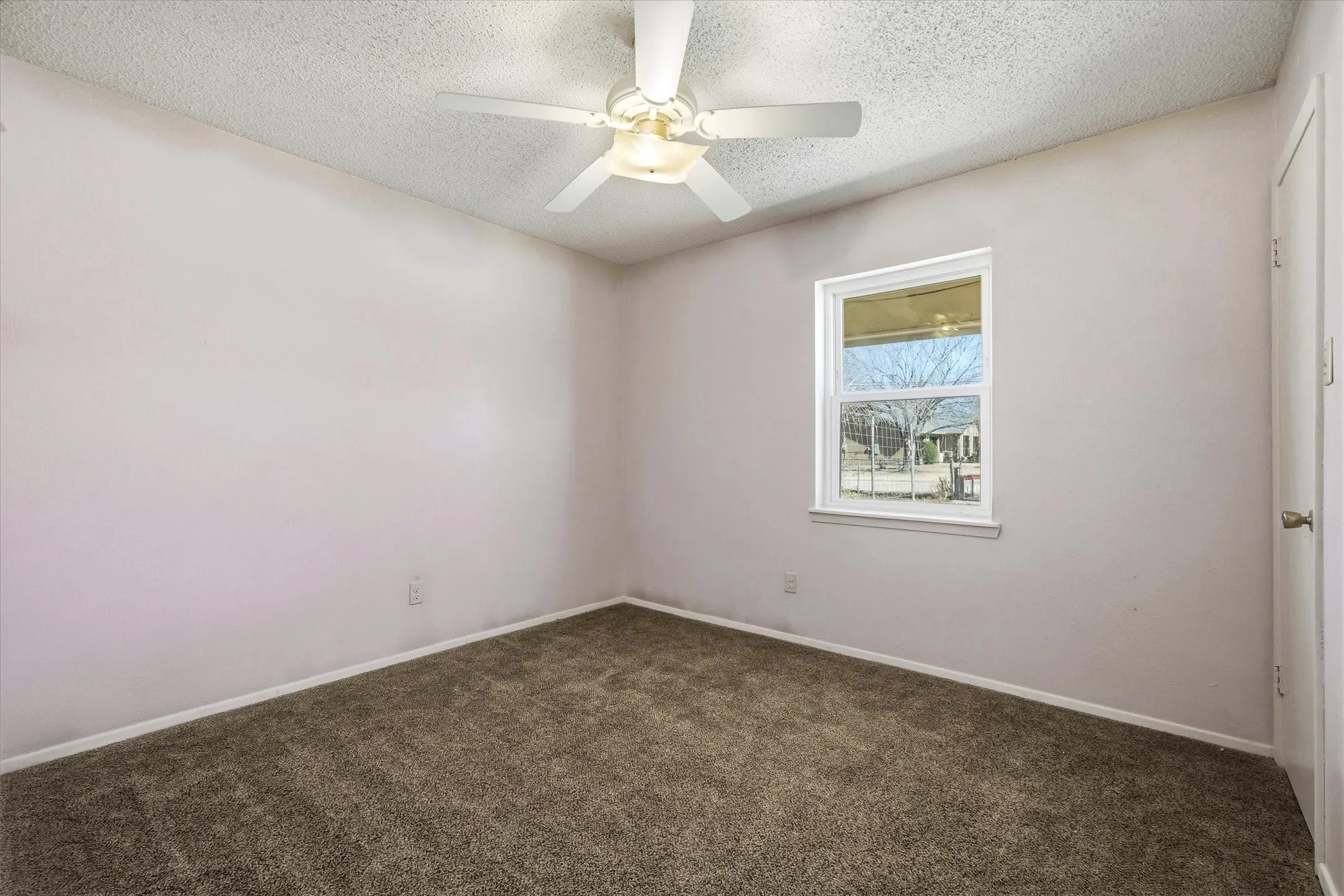 Textured ceiling with a ceiling fan light fixture, neutral wall paint, and plush carpet flooring