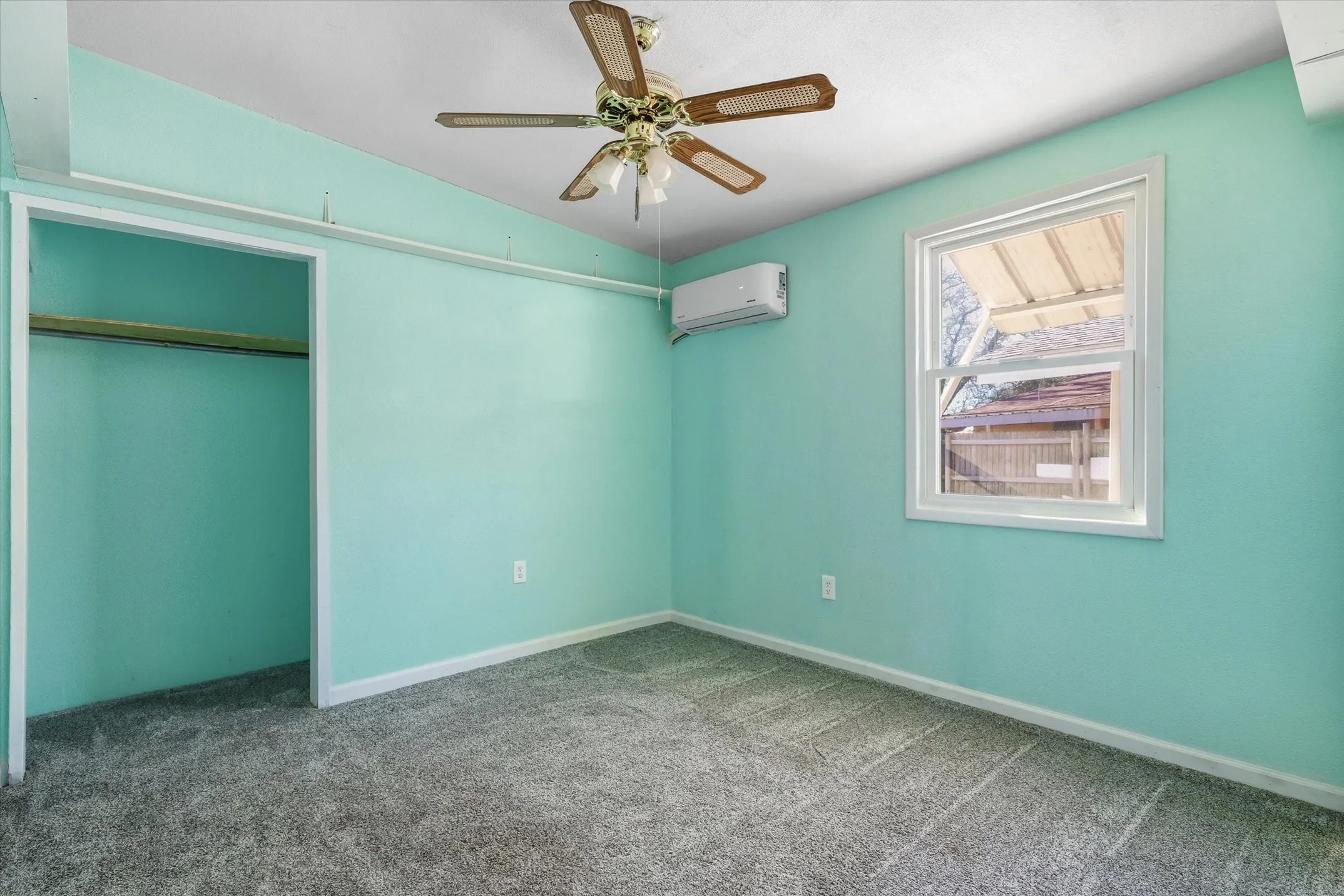 Room featuring a single-pane window, ceiling fan, ductless mini-split unit, and a closet with a built-in hanging rod