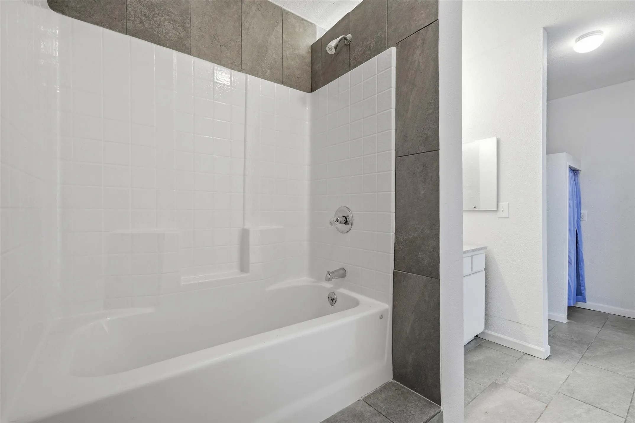 Bathtub and shower combination featuring white subway tile surround and dark grey large format tile accent