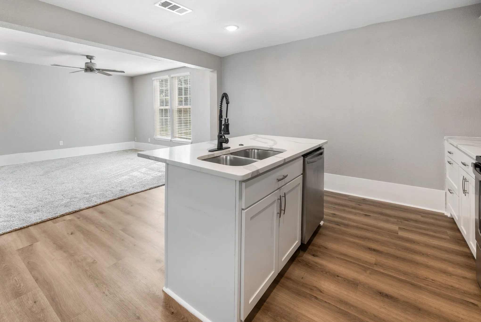 Kitchen island with a double basin sink, white cabinetry, and a black faucet