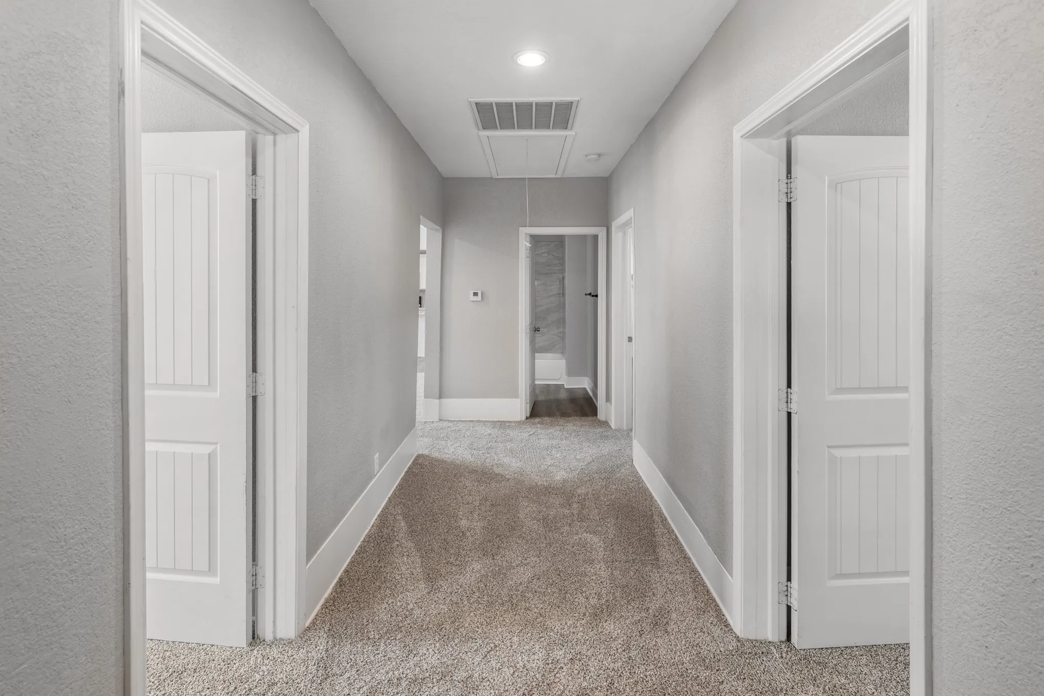 Carpeted hallway with light gray walls, white trim, and recessed lighting