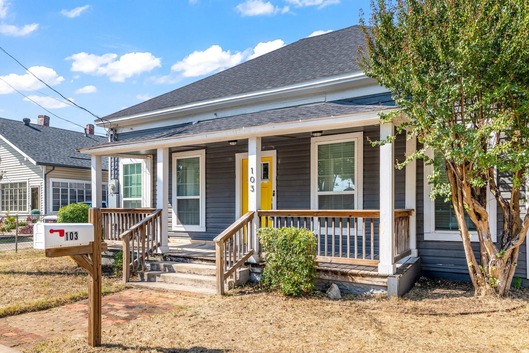 Single-story property with dark gray siding, a covered front porch, and a contrasting yellow entry door