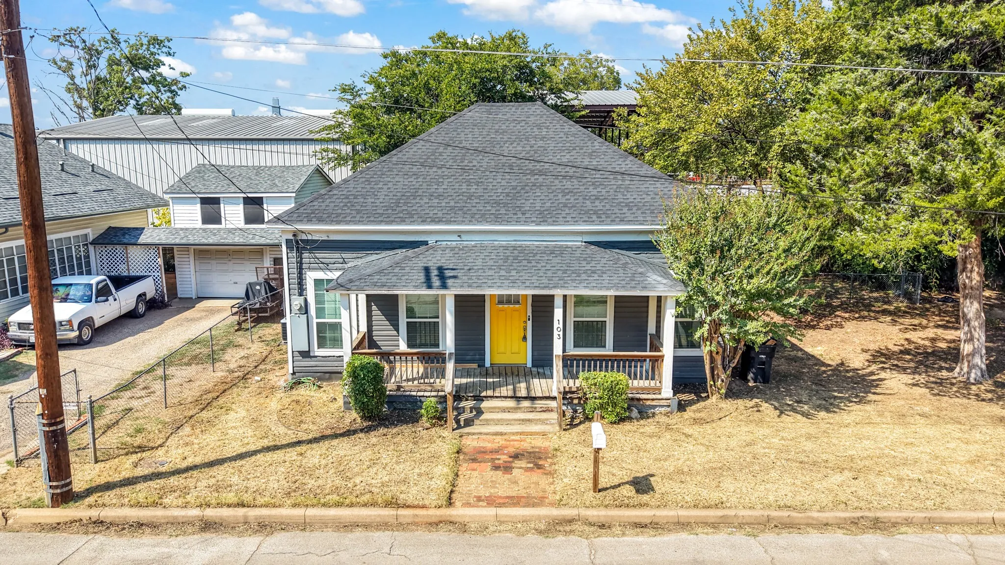 Traditional-style home featuring a covered front porch with wood railings, a gray exterior, and a prominent yellow front door