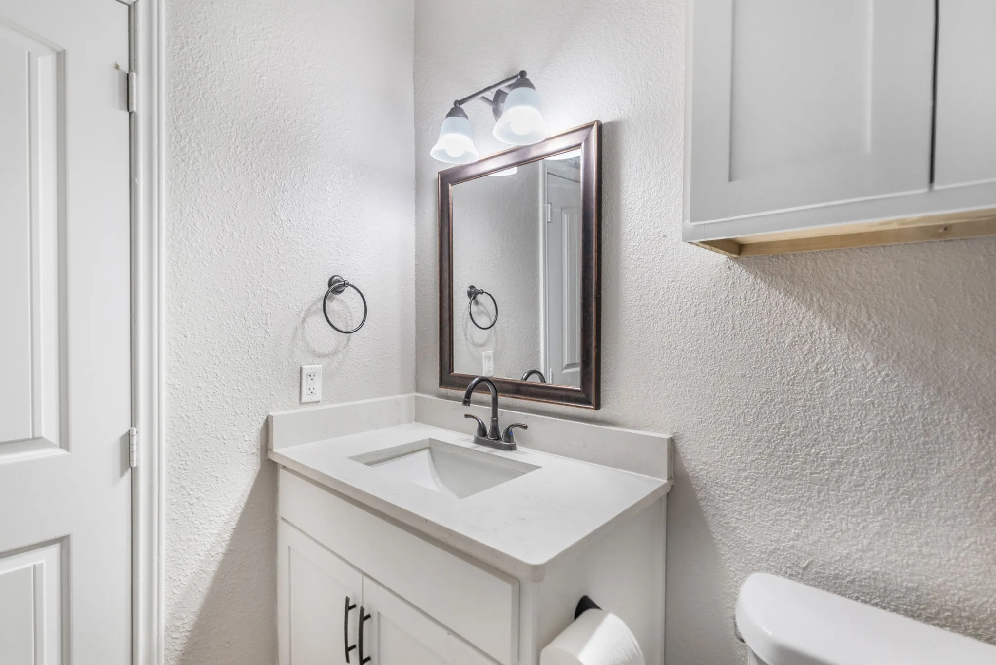 White shaker-style vanity with a single basin sink and a light-colored countertop