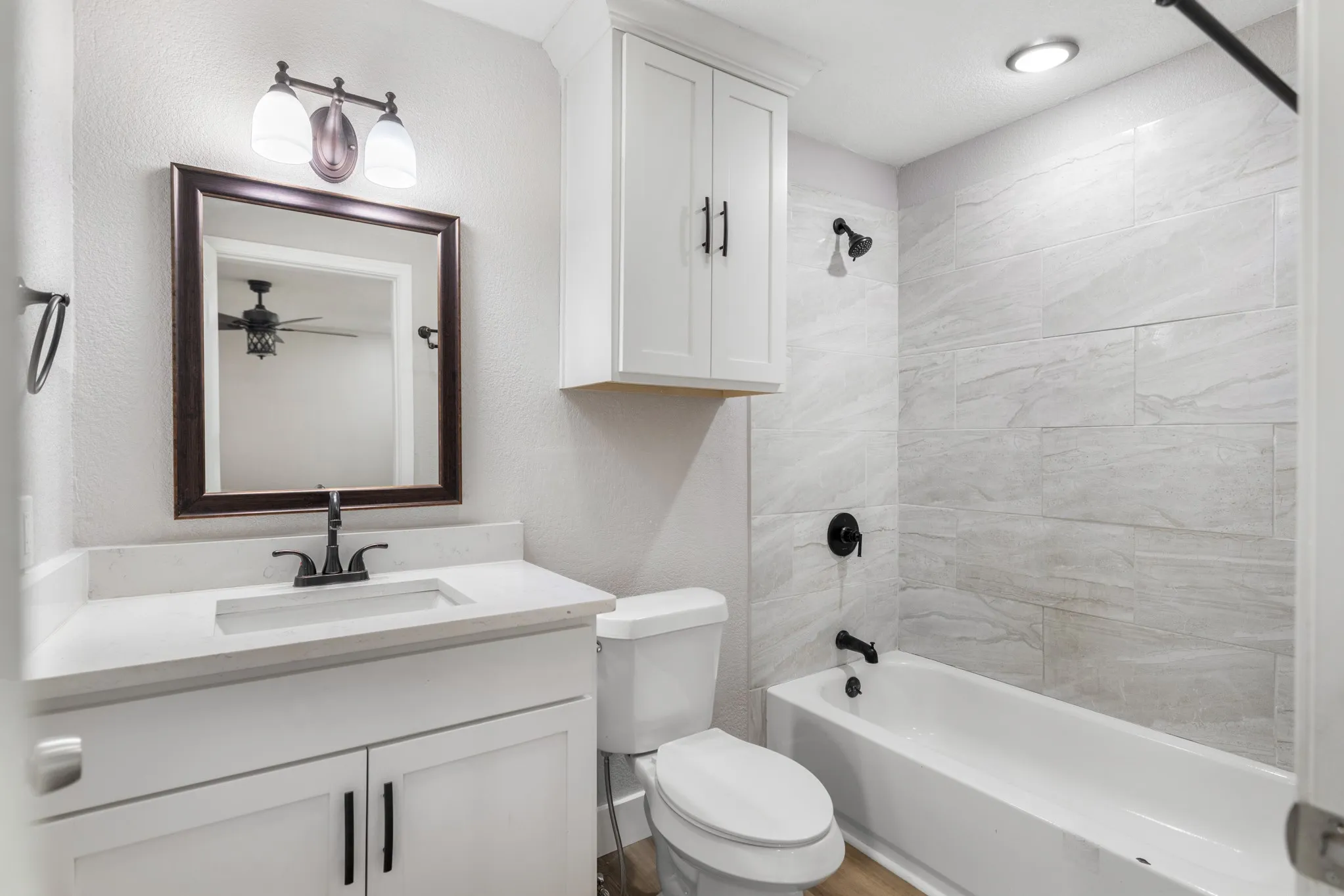 White vanity with an integrated sink and matte black faucet, framed mirror, and a three-light fixture