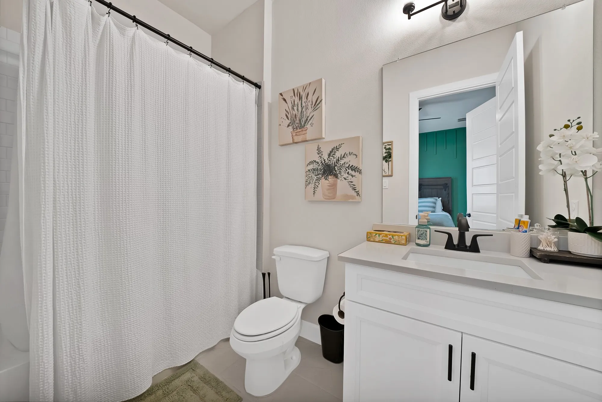 White vanity with shaker-style cabinetry, a built-in rectangular sink, and a light-toned countertop
