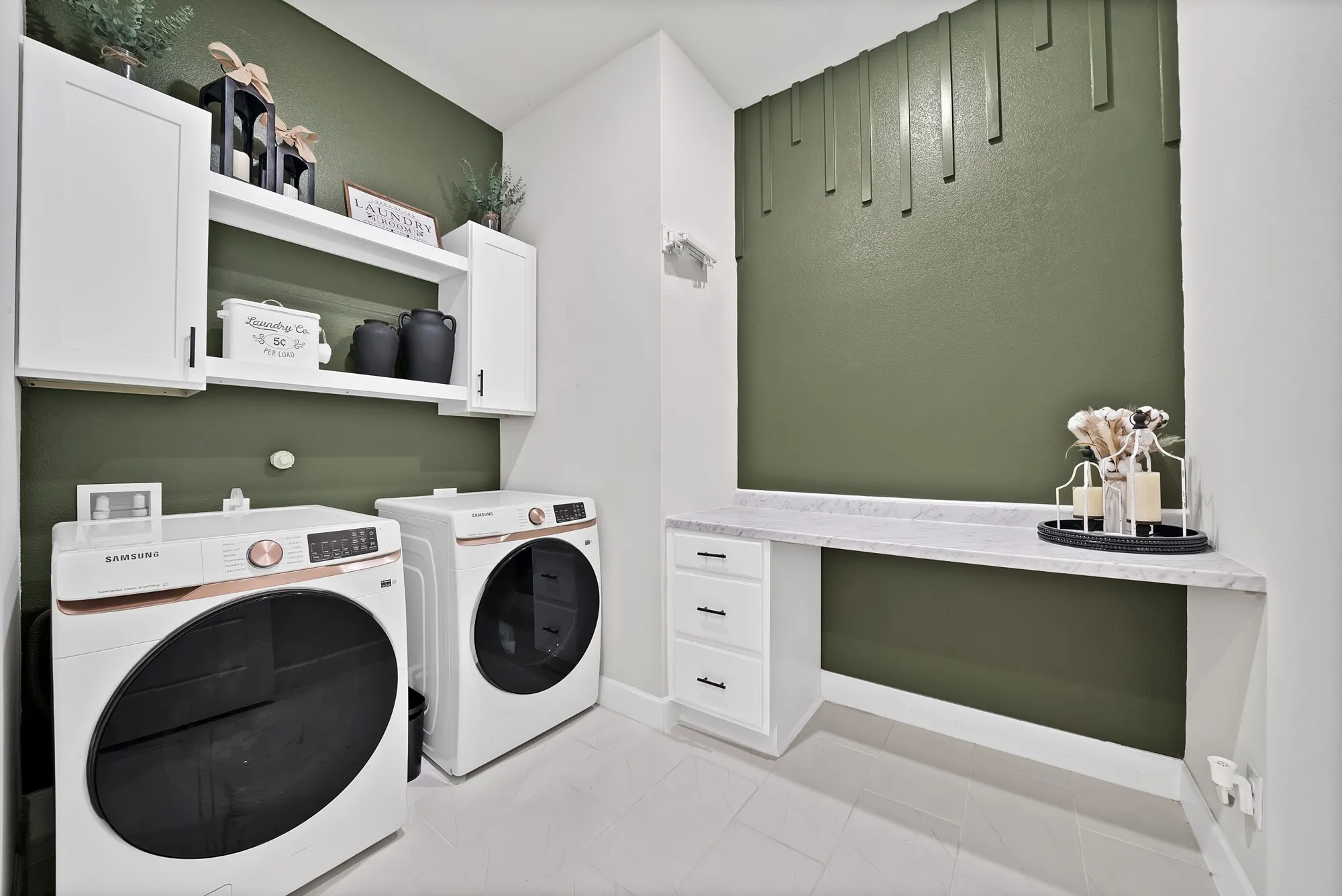 Built-in white cabinetry, white floating shelf, white built-in desk with drawers, white countertop, and green accent walls