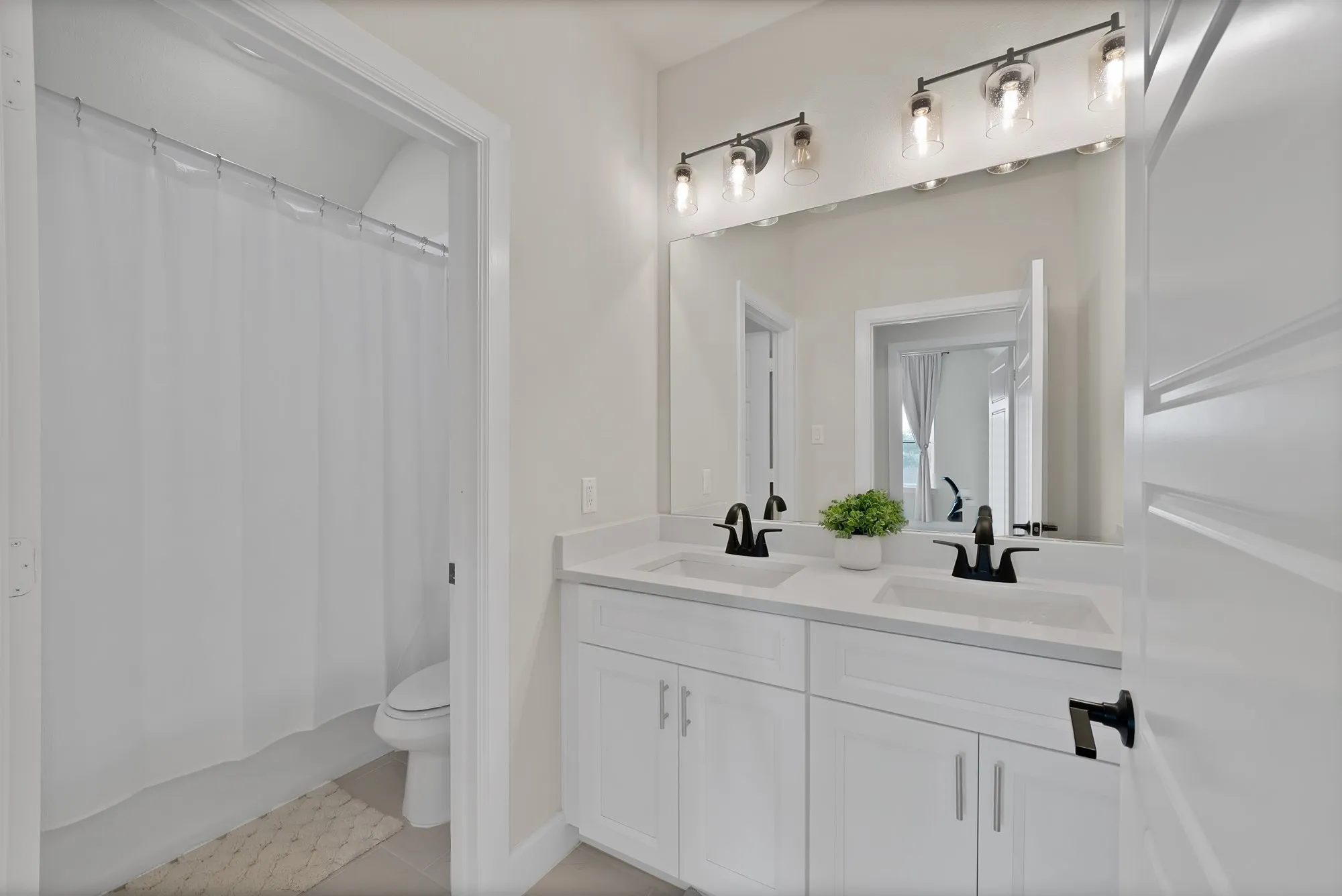 Dual vanity with white cabinetry, matte black fixtures, and a spacious mirror