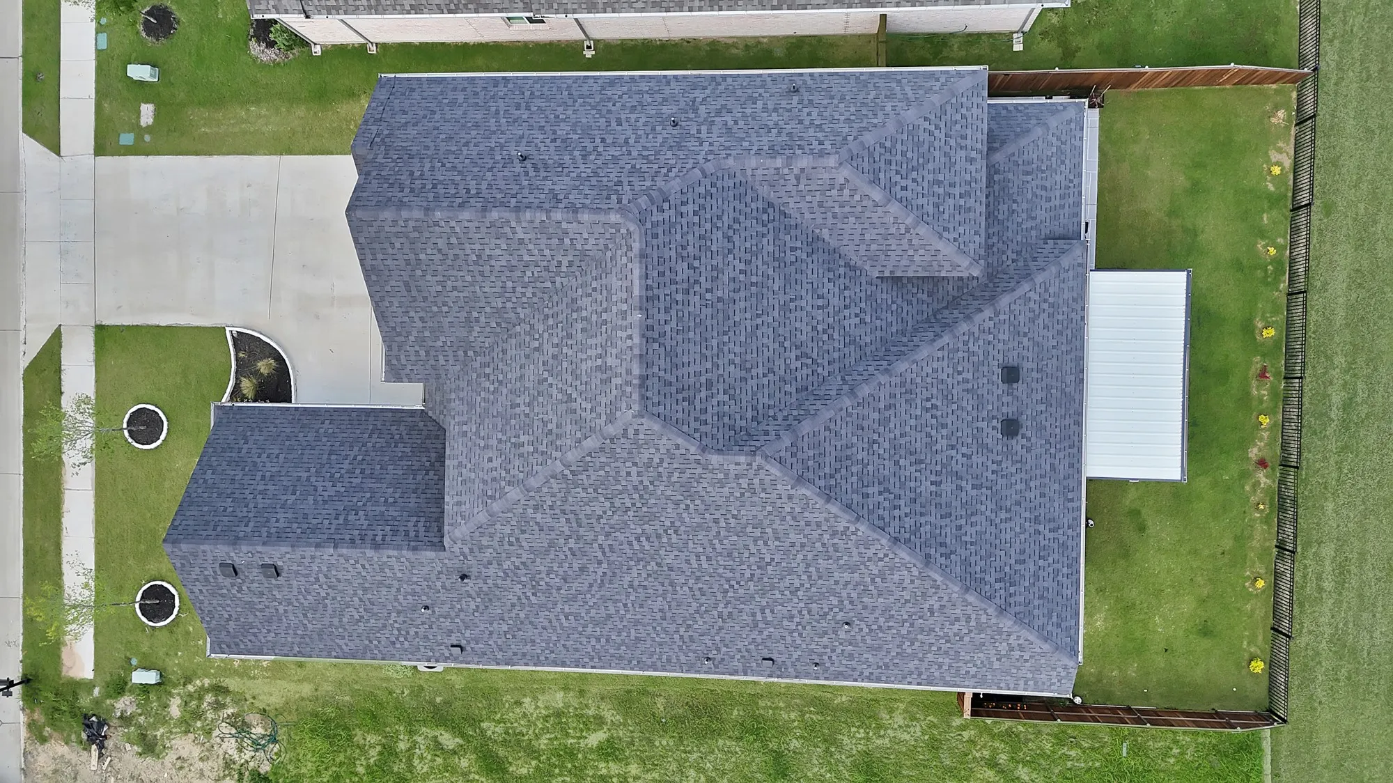 Asphalt shingle roofing, concrete driveway, manicured lawn, and a fenced backyard