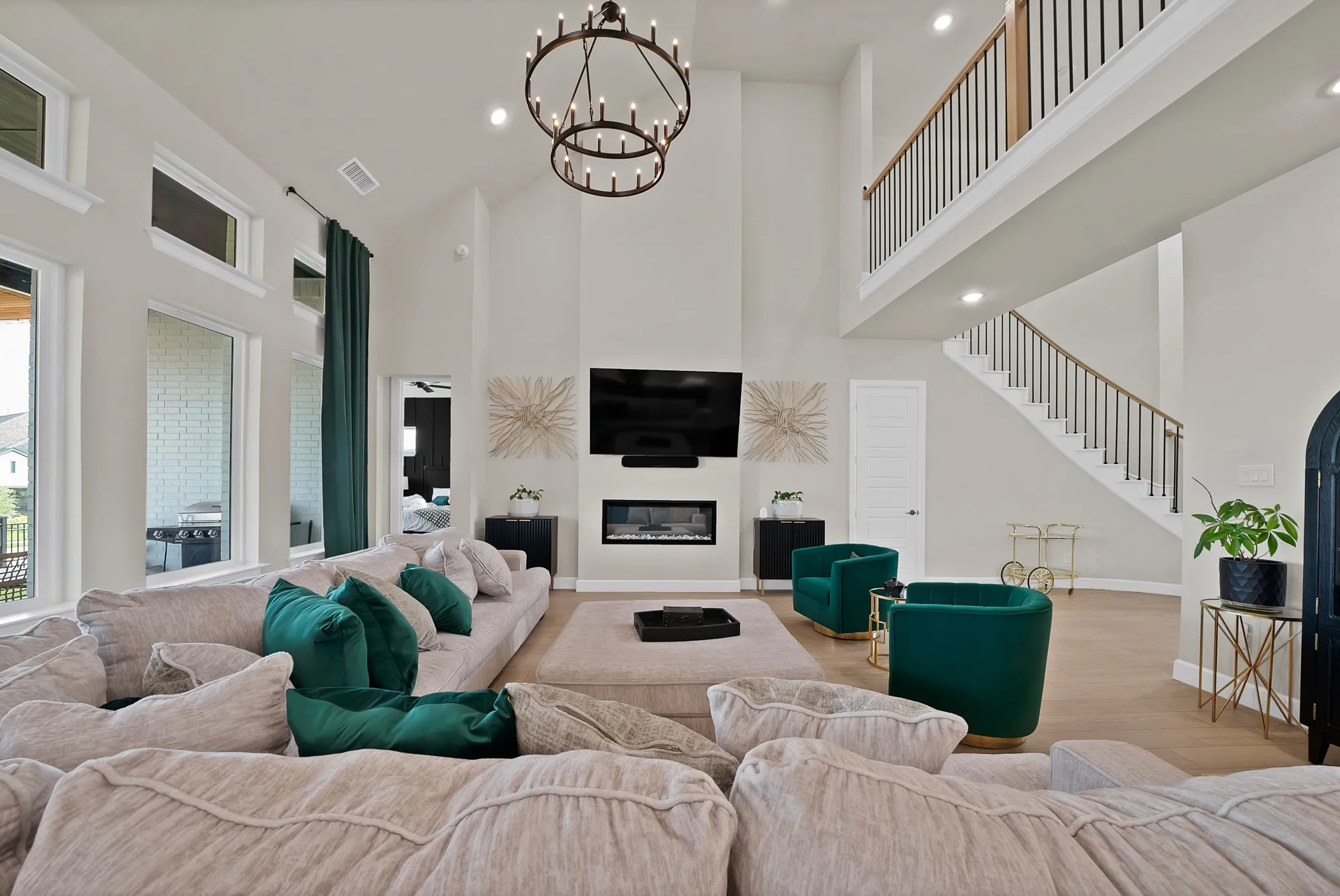 Two-story ceiling, integrated fireplace, wood-finish flooring, staircase with metal and wood banister, and large picture windows