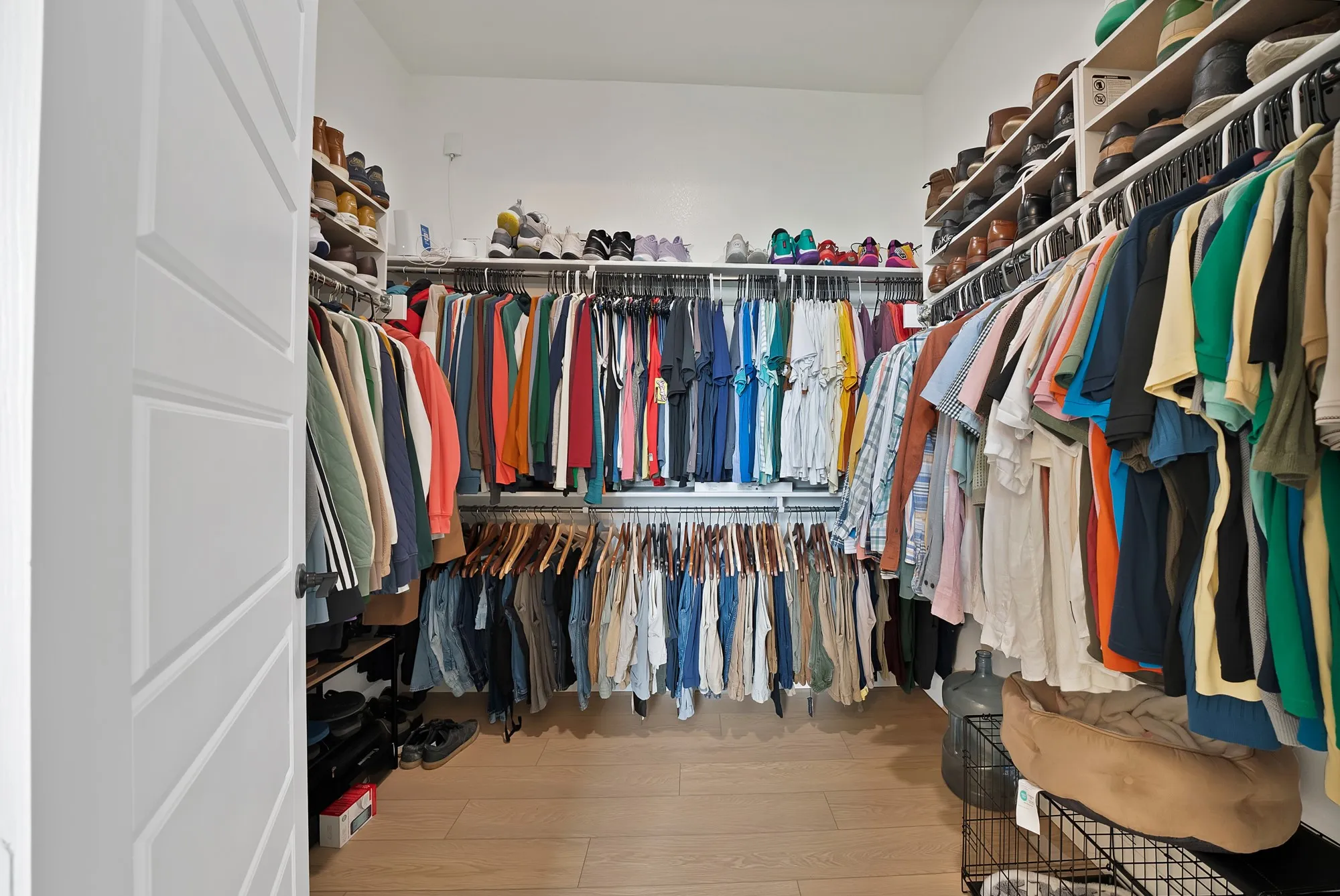 Walk-in closet with extensive built-in shelving, multiple hanging rods, and wood-finish flooring