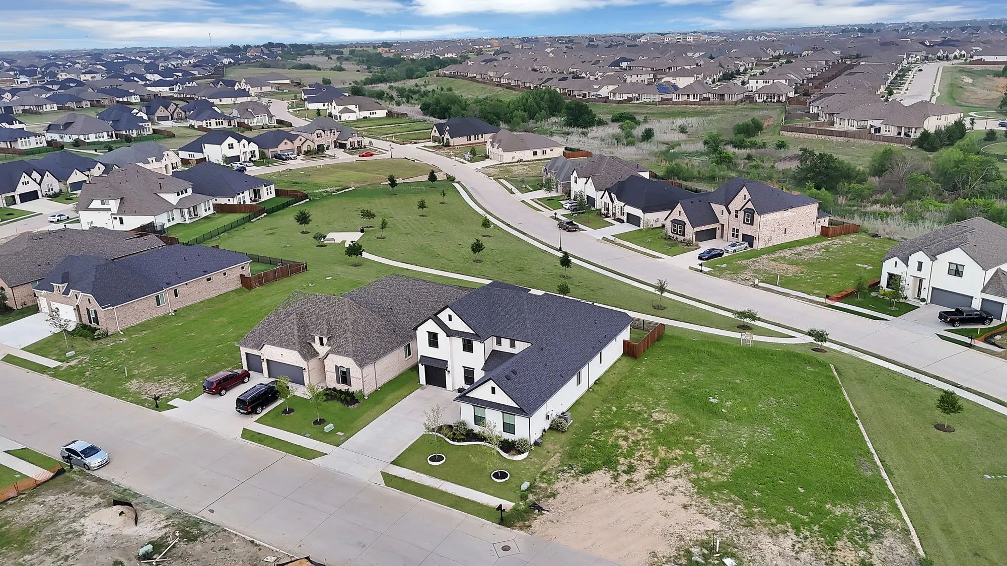 Aerial perspective showcasing a residential development with multiple single-family homes, paved streets, and green spaces