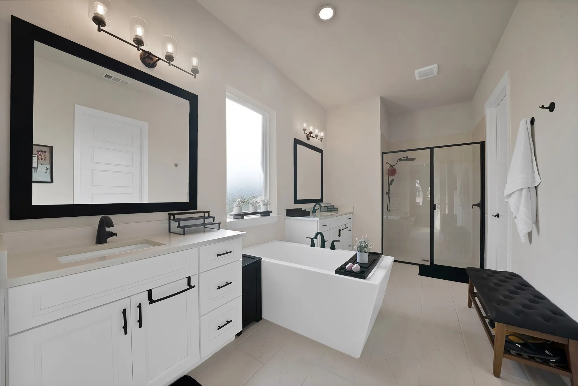 Dual vanity with white cabinetry and integrated sinks, a freestanding soaking tub, and a separate glass-enclosed shower
