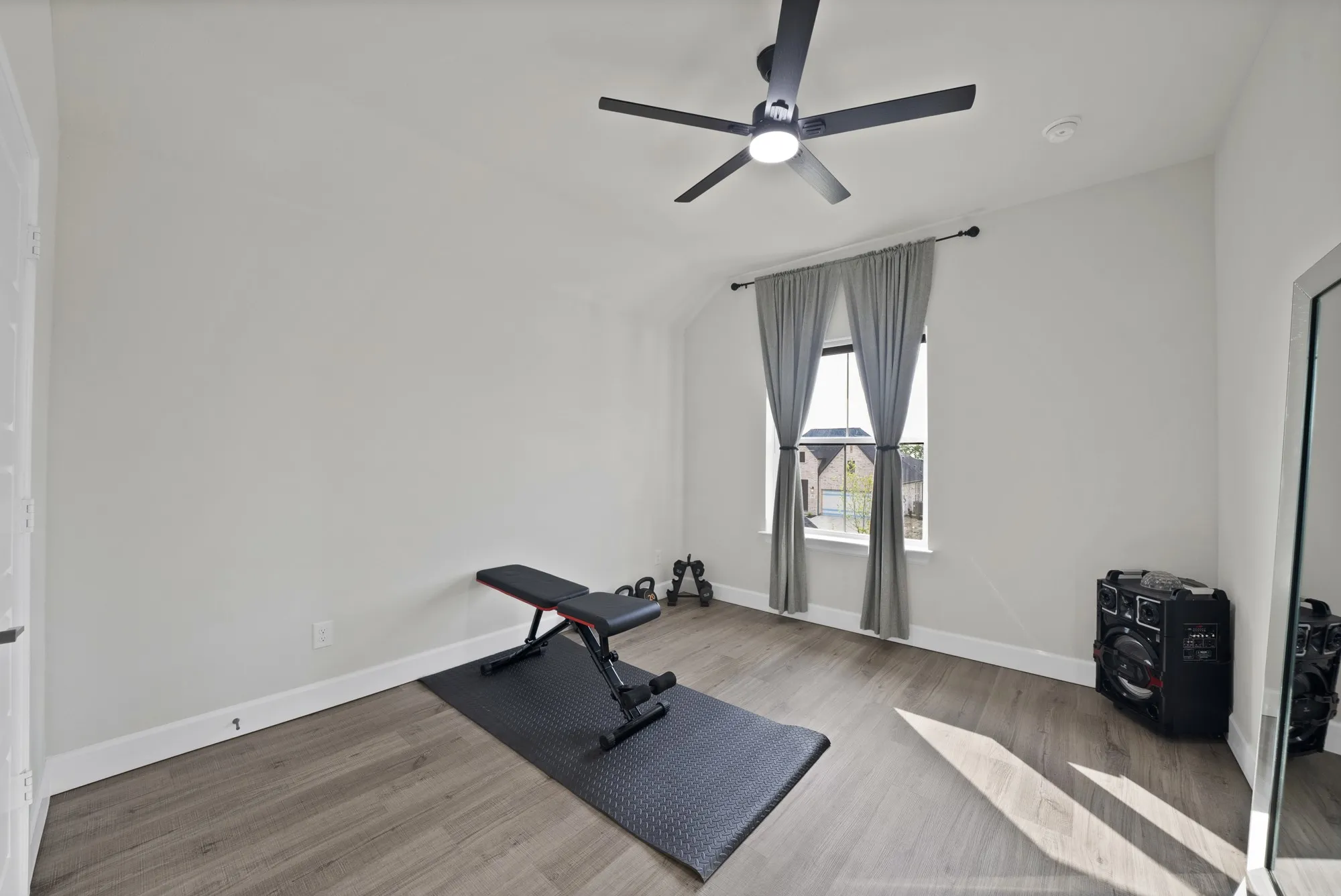 Neutral wall tones, wood-finish flooring, a window with drapery, a ceiling fan, and recessed lighting