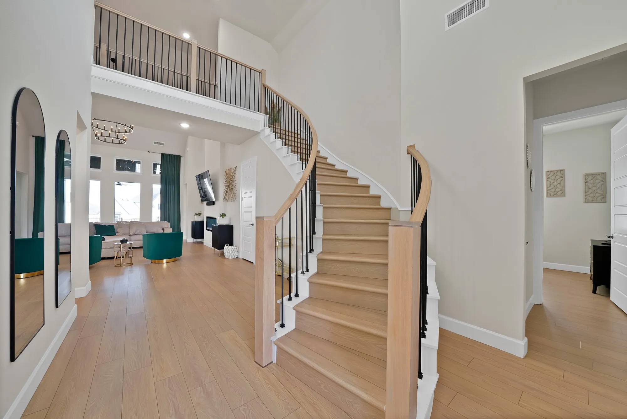 Curved staircase with wood-finish treads and risers, black metal balusters, and a light wood-finish handrail