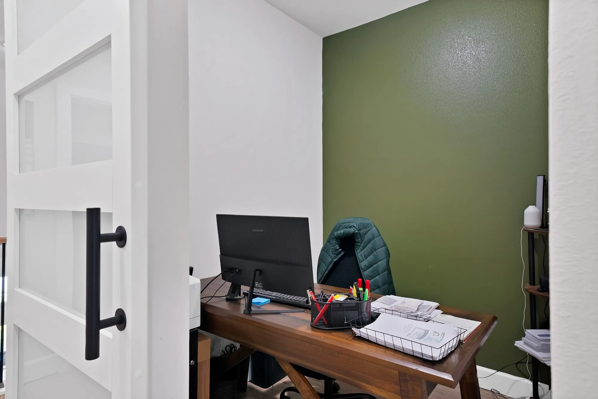 Recessed office space with a contrasting accent wall, featuring a sliding barn door with frosted glass panels and matte black hardware