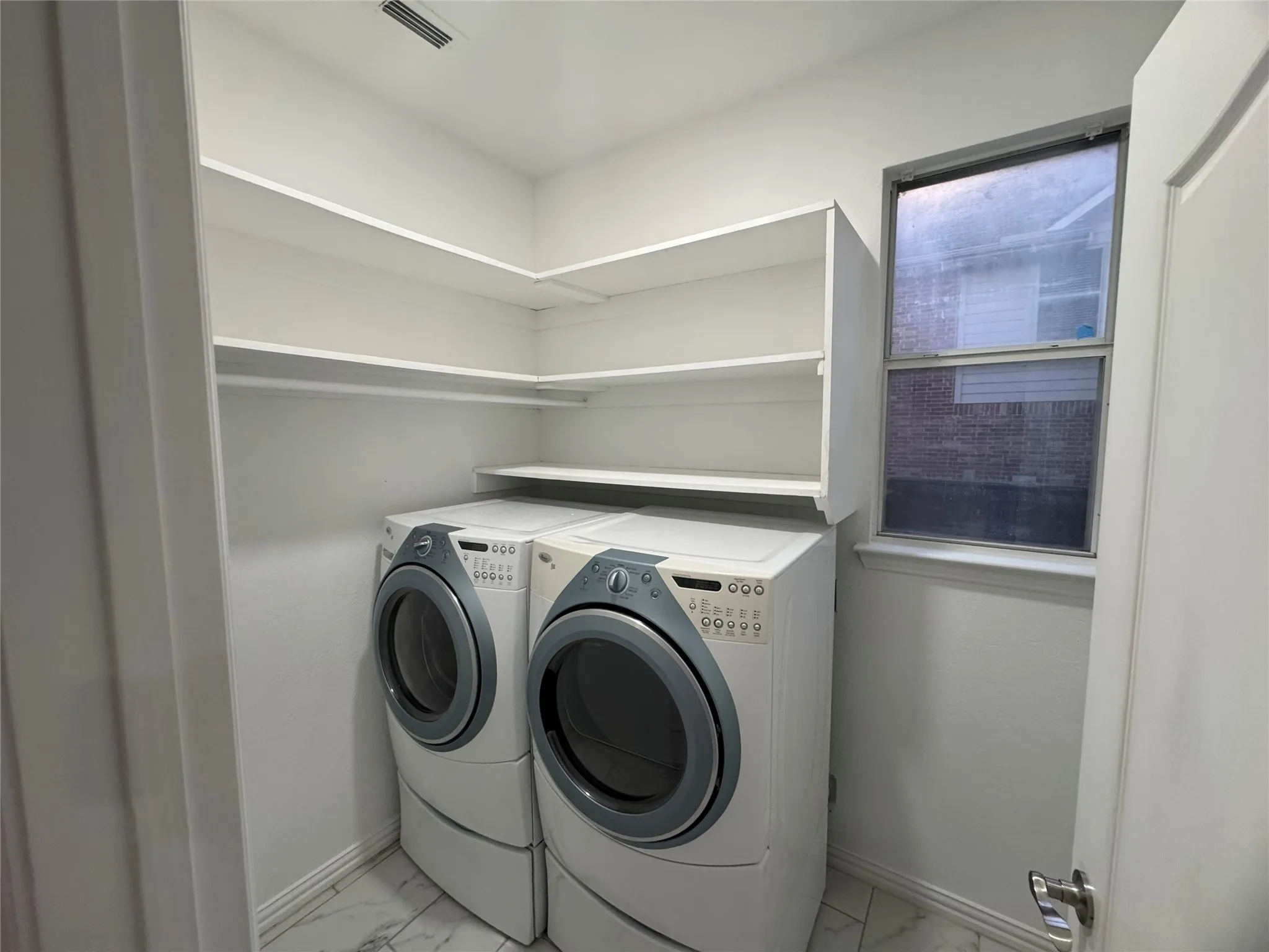 Laundry area featuring built-in shelving, a window, and white tile flooring