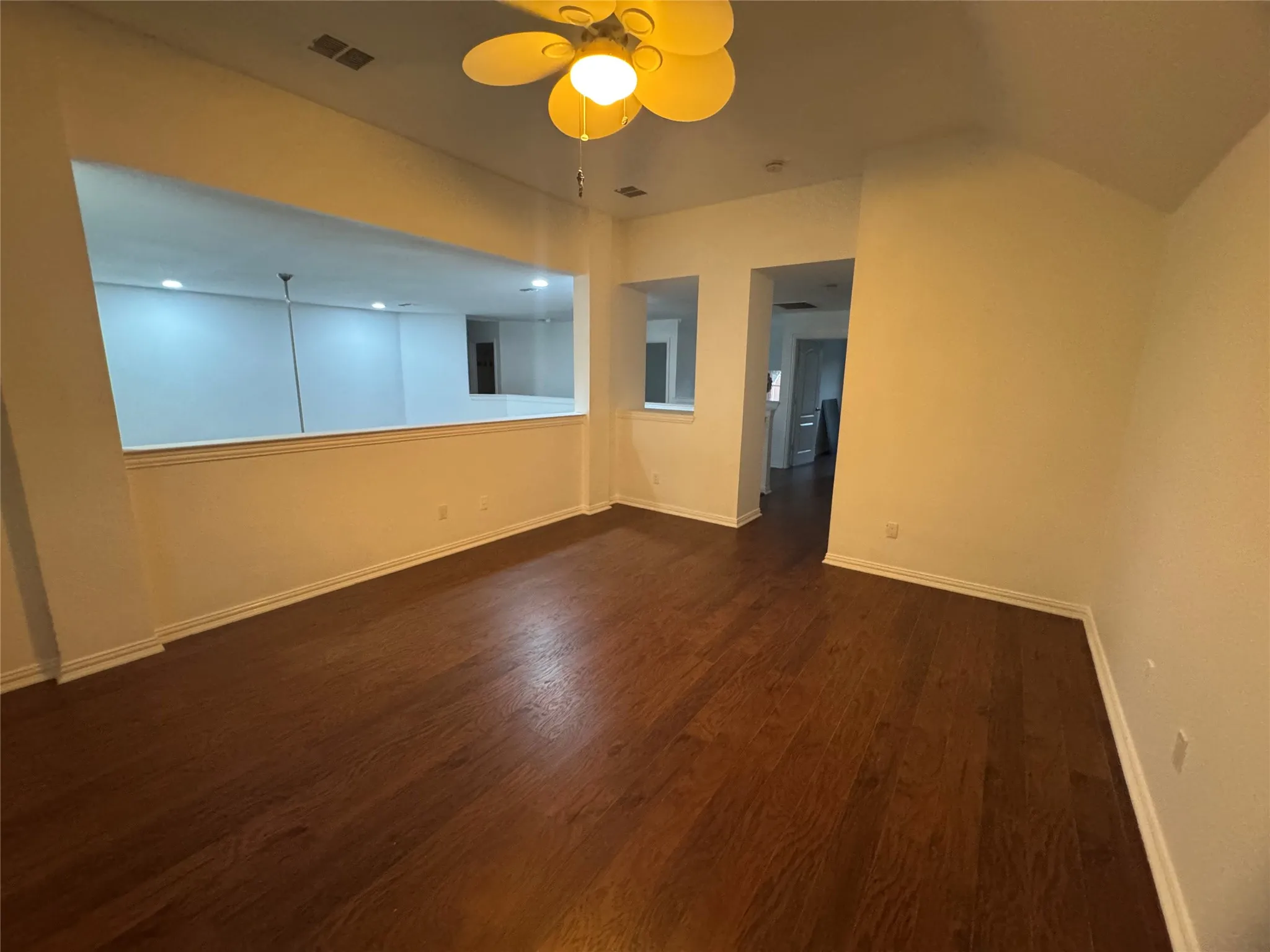 Wood-finish flooring, ceiling fan with integrated lighting, recessed wall opening, and interior wall opening