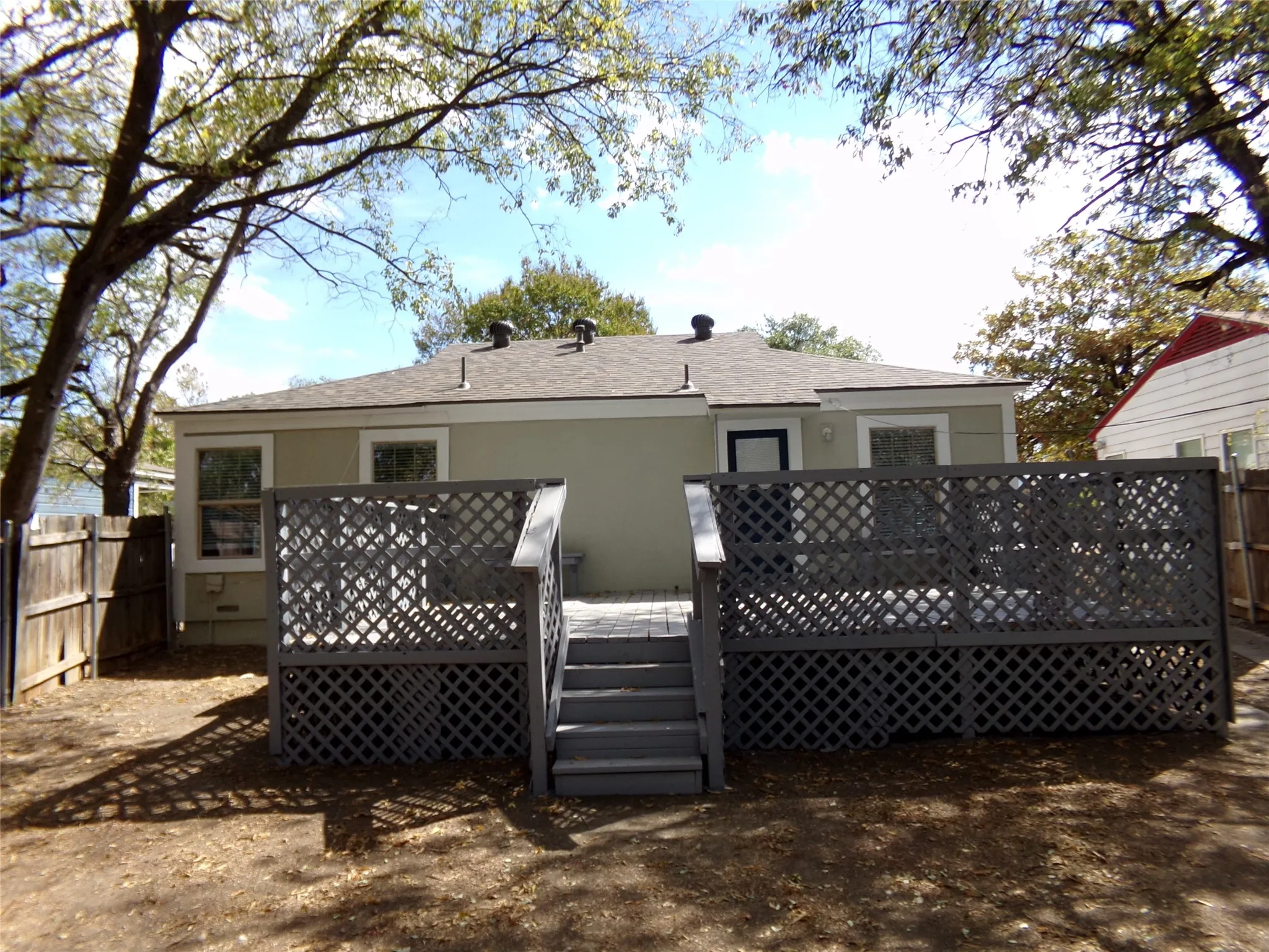Rear exterior featuring a composite deck with lattice skirting, steps, and a wooden privacy fence