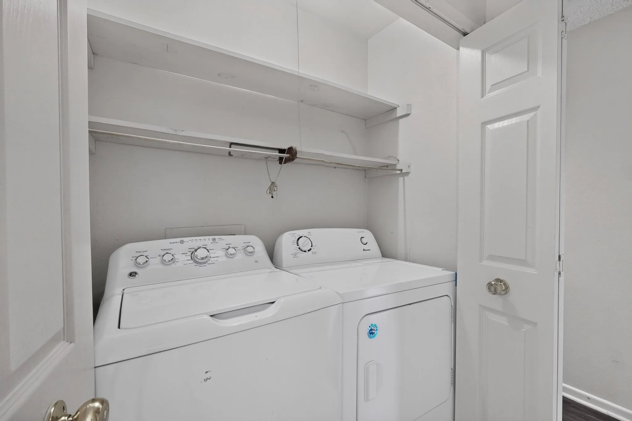 Laundry closet featuring a built-in shelf and white paneled doors
