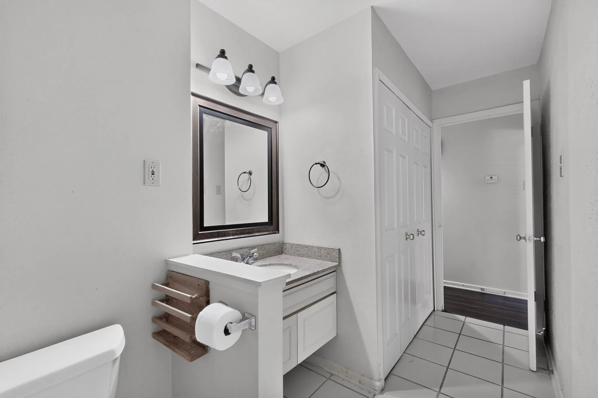 Bathroom featuring a vanity with an integrated sink, framed mirror, and a three-light fixture