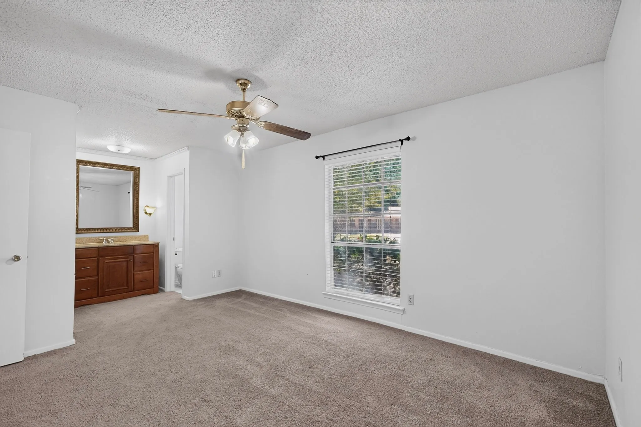 Wall-to-wall carpeting, window with blinds, ceiling fan, and an integrated vanity with a mirror