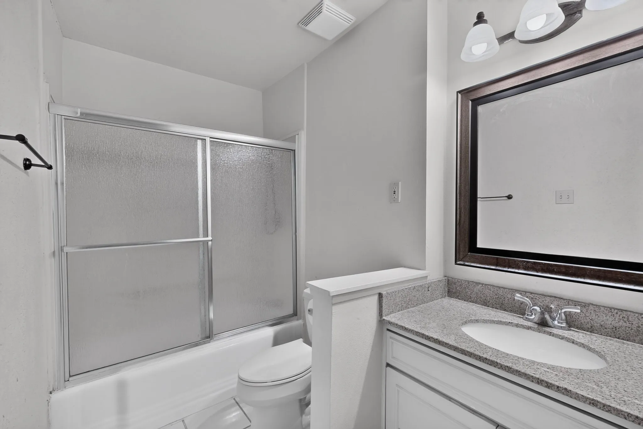 White vanity with a polished countertop, undermount sink, and chrome fixtures