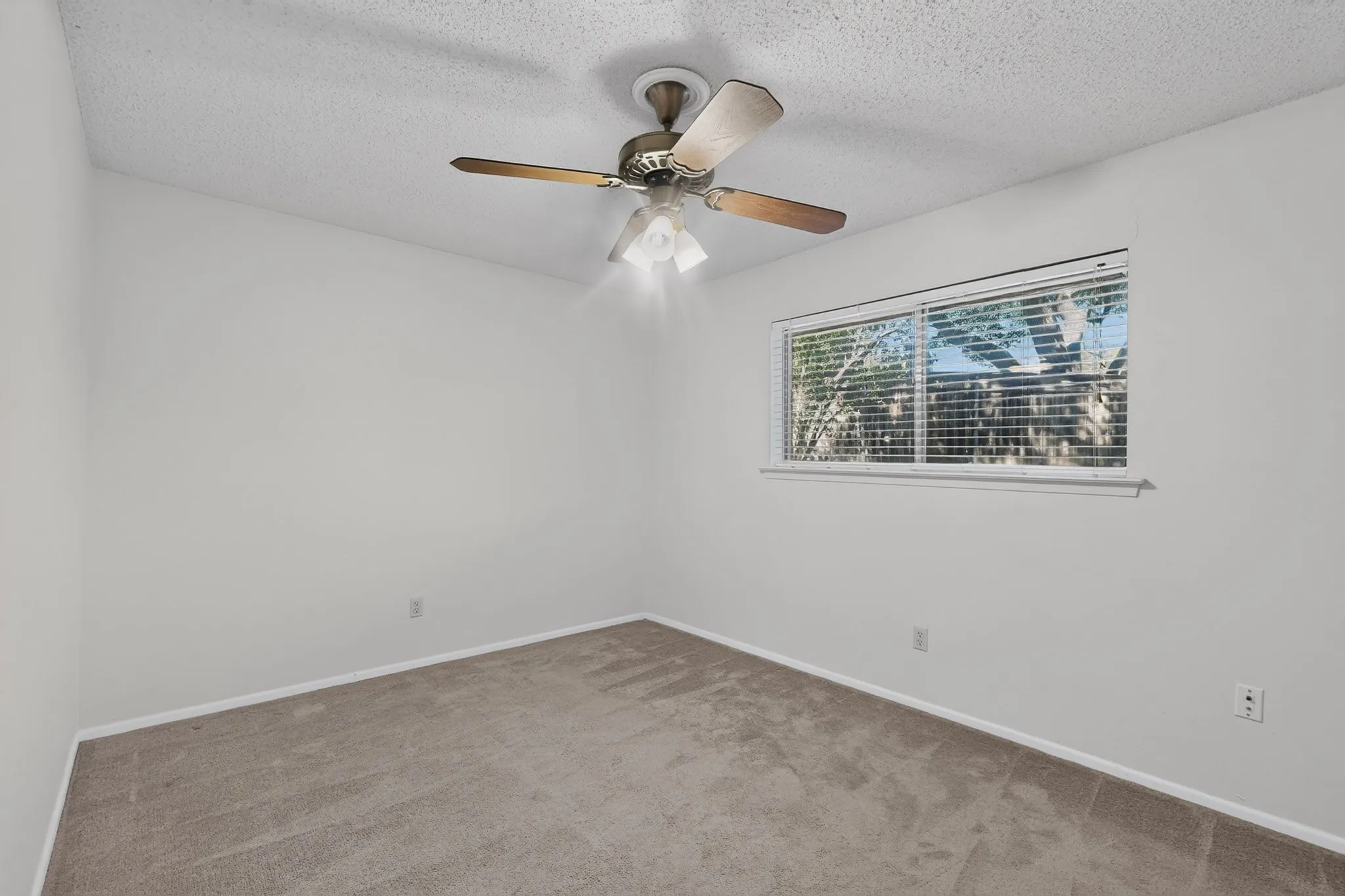 Recessed window with horizontal blinds, overhead ceiling fan with light fixture, textured ceiling, and carpeting