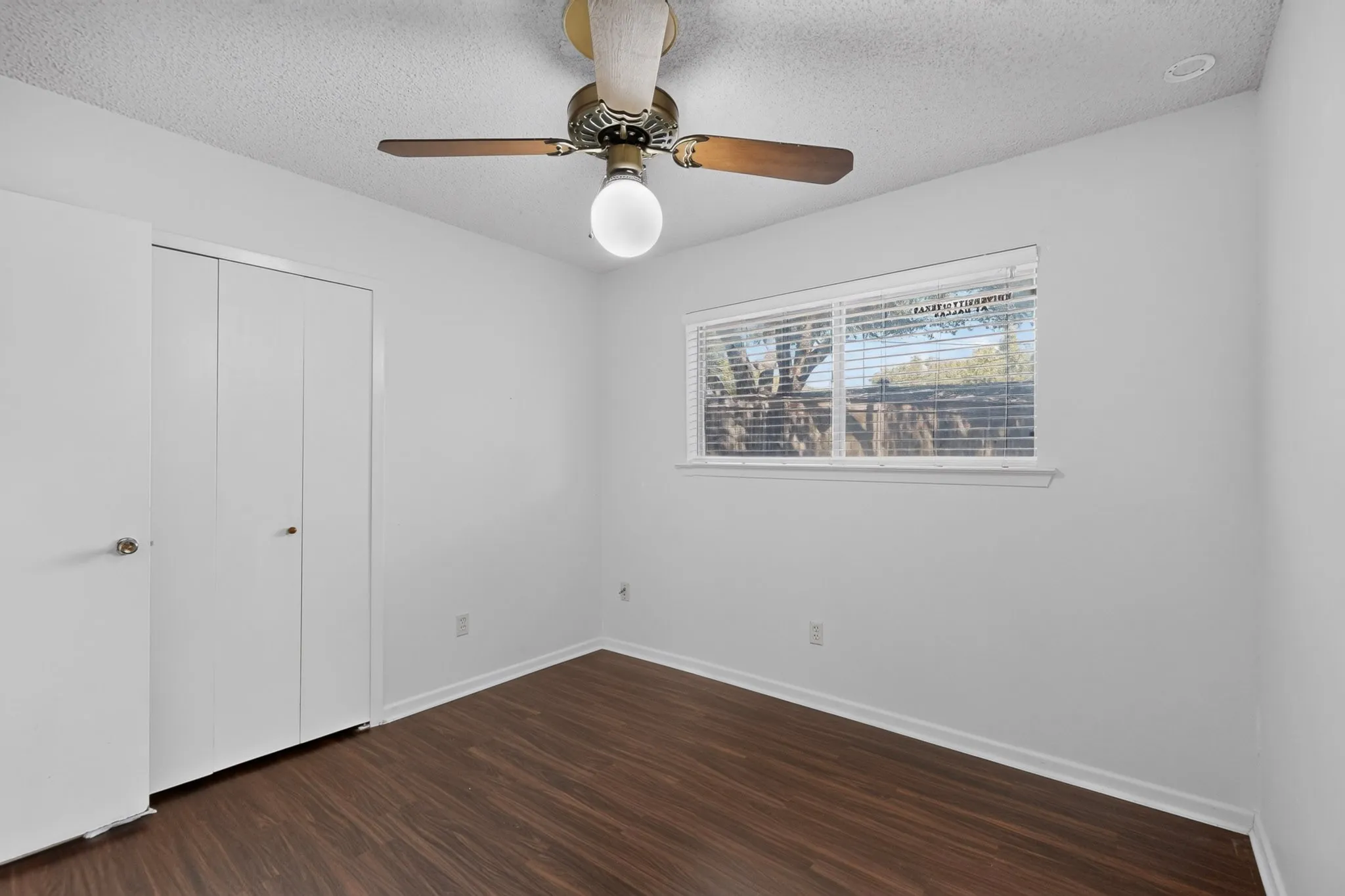 Wood-finish flooring, white walls, and a window with horizontal blinds