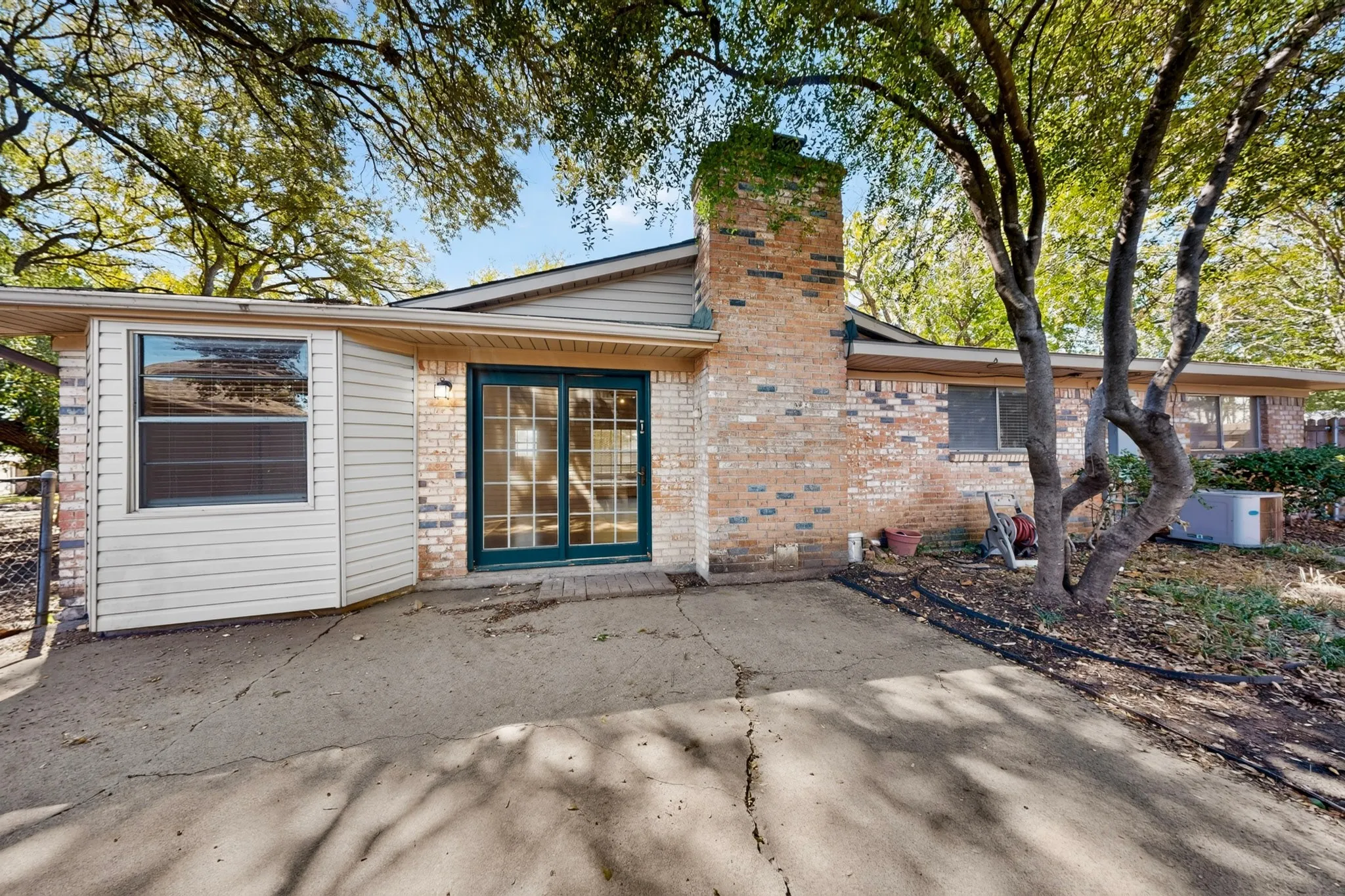 Brick exterior with a prominent chimney, double-pane sliding glass doors, and a covered patio area