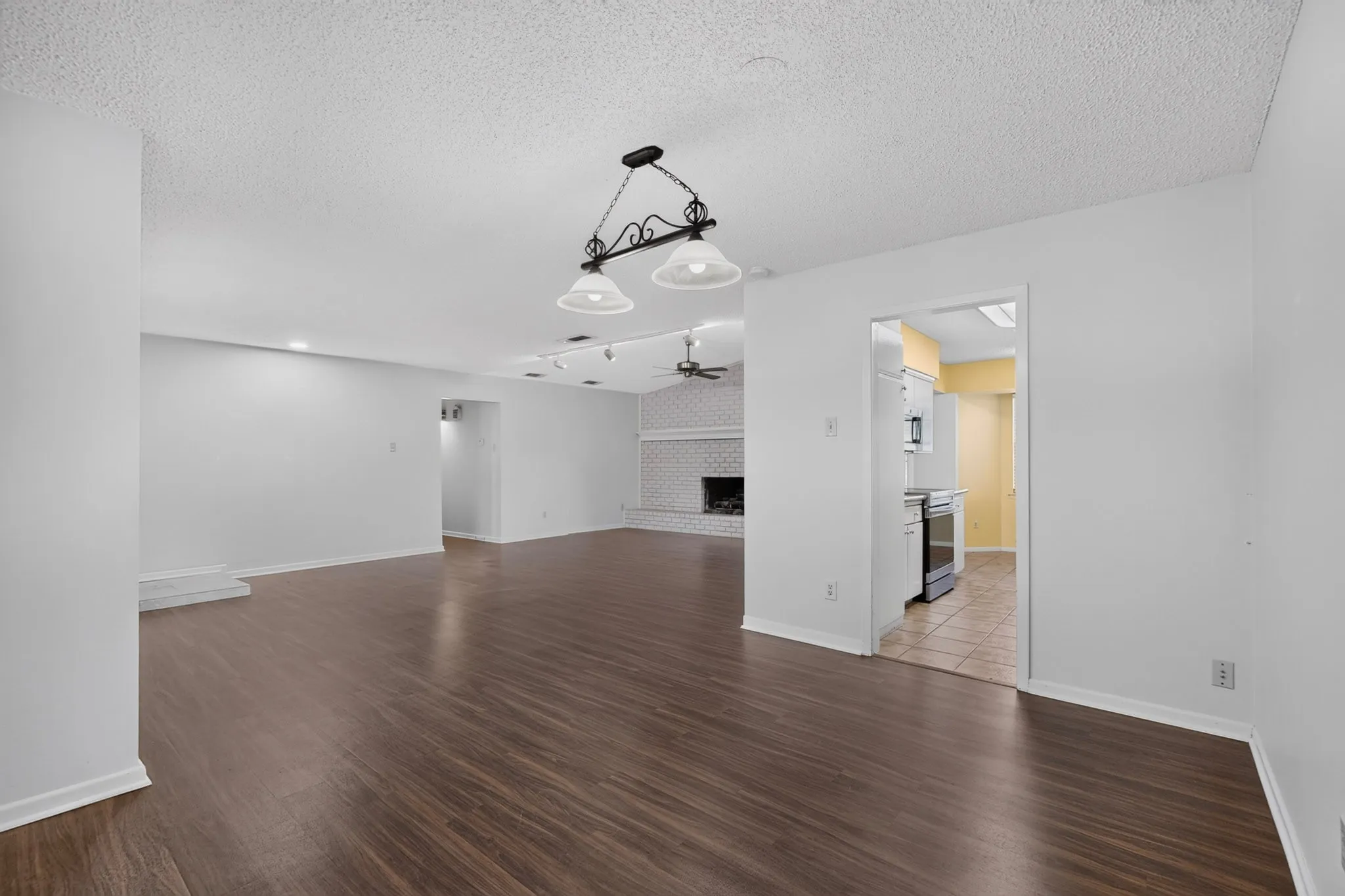 Spacious interior featuring wood-finish flooring, a white brick fireplace, and recessed lighting