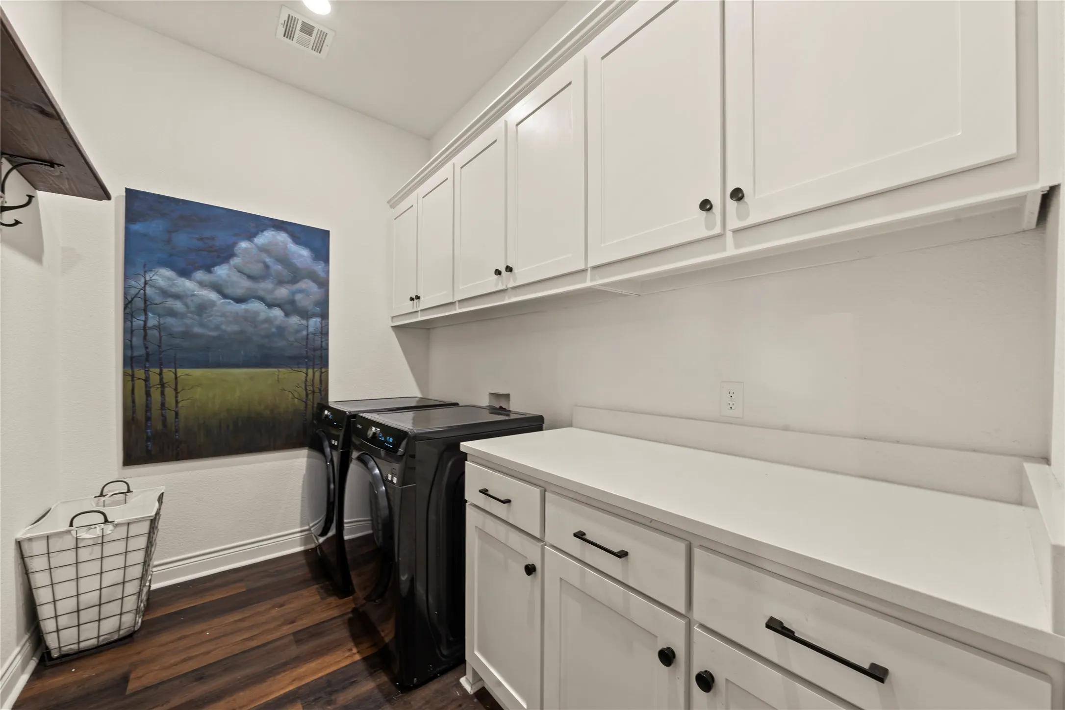 Wood-finish flooring, white shaker cabinetry, white countertop, and a storage shelf with hooks