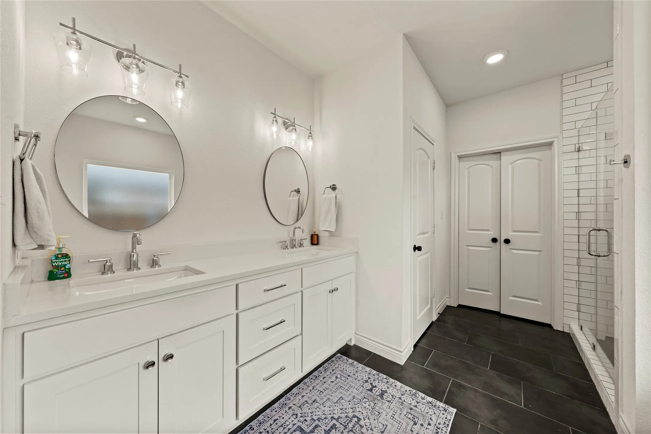 Dual vanity with white cabinetry and integrated sinks, complemented by circular mirrors